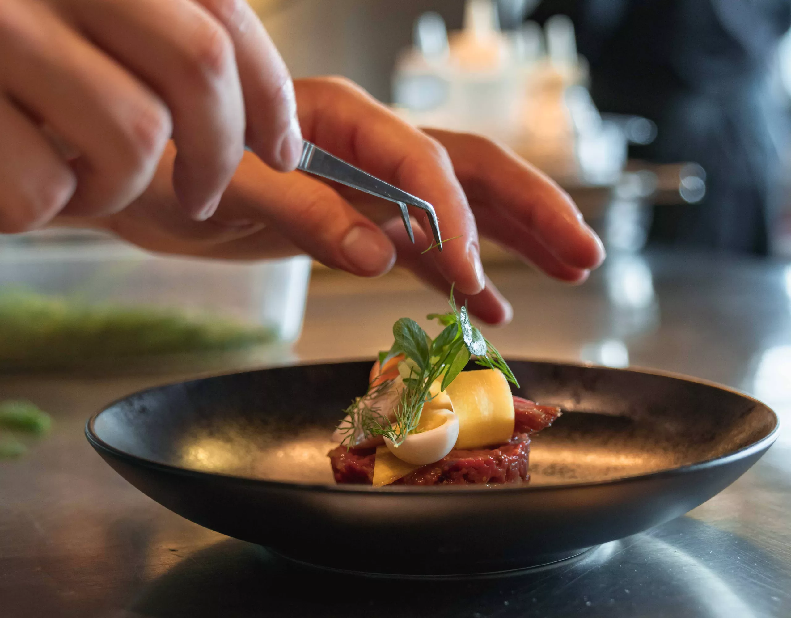 fine beef tartare is garnished with the help of tweezers in the bavarie 