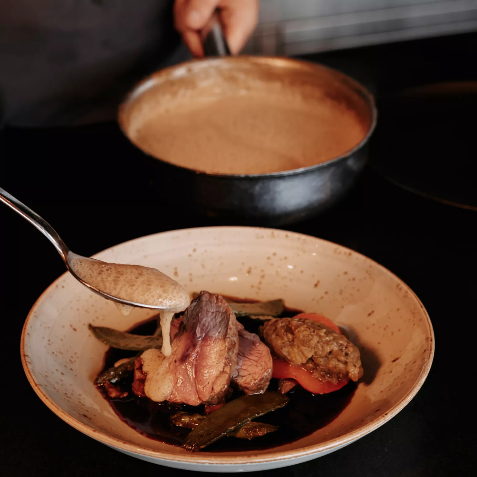 chef pours sauce on fine beef dish