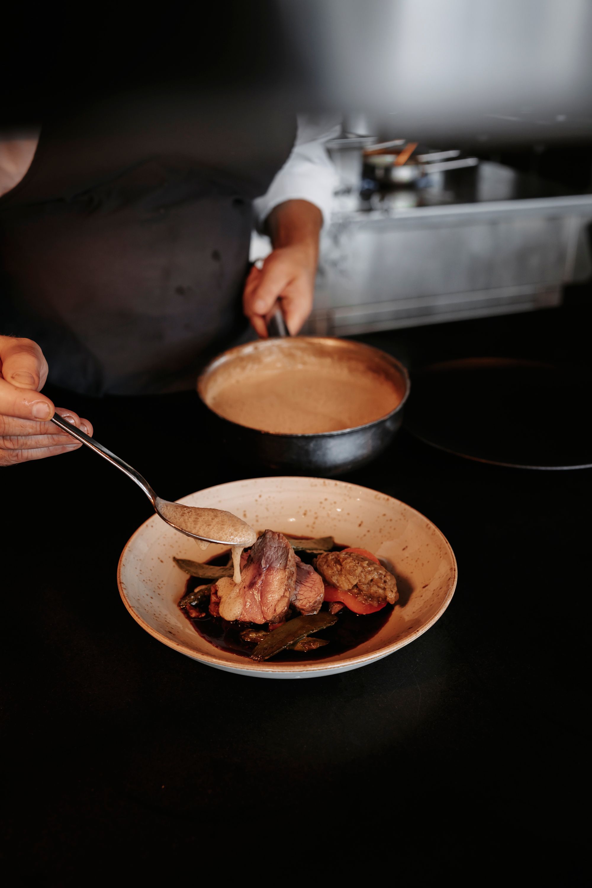 chef pours sauce on fine beef dish