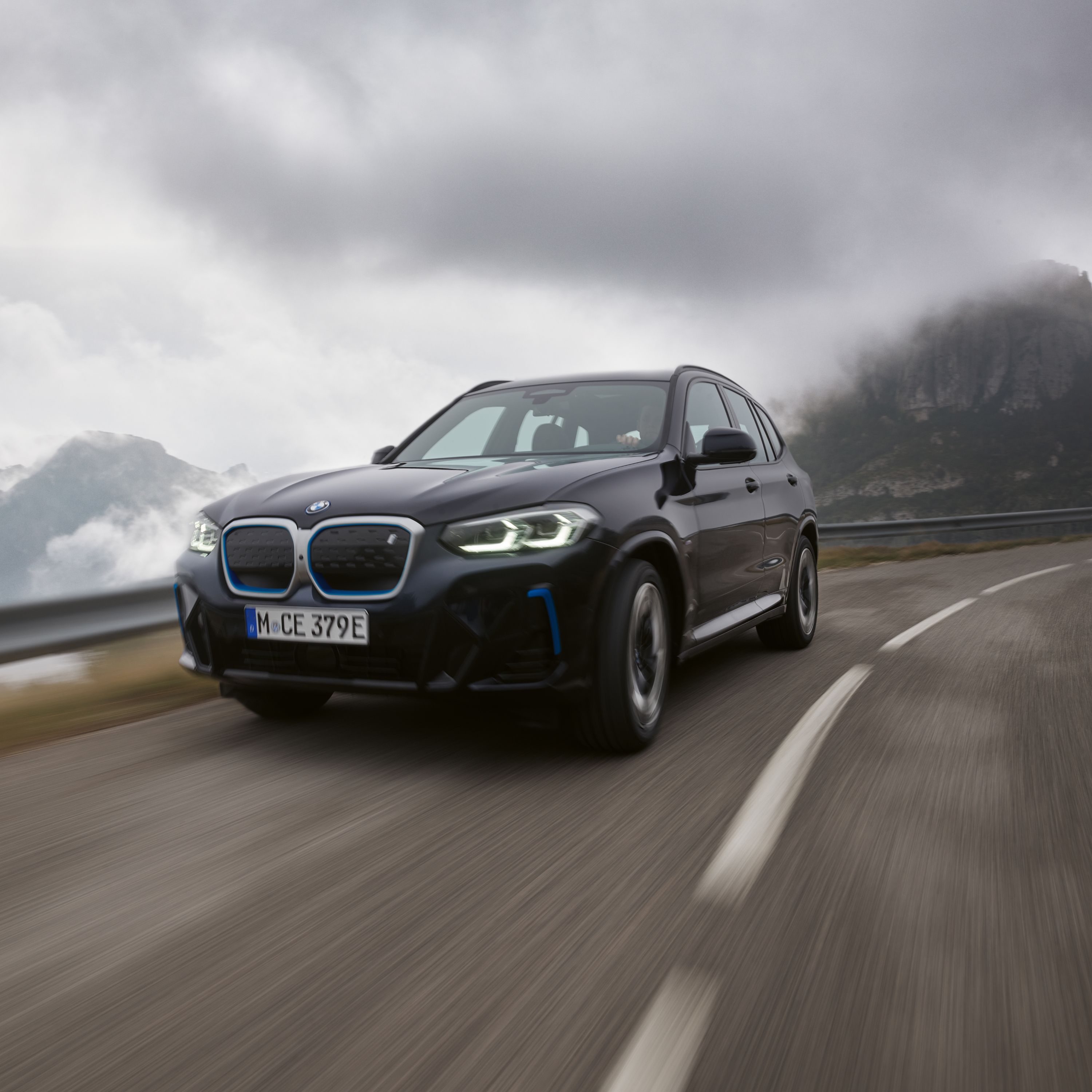 BMW iX3 G08 SUV surrounded by storm clouds on a mountain pass