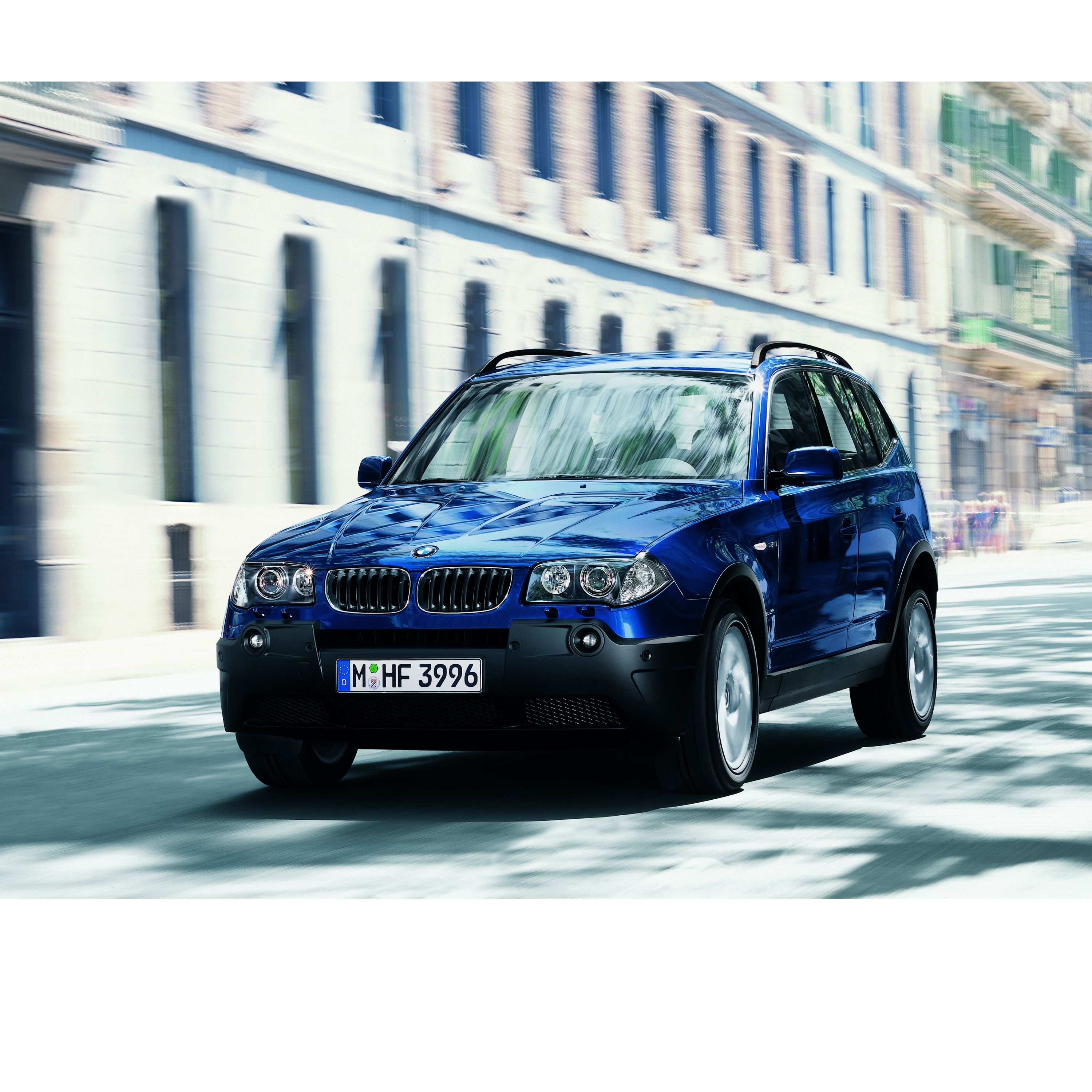 BMW X3 E83 SUV on a road in front of a historic European city center backdrop