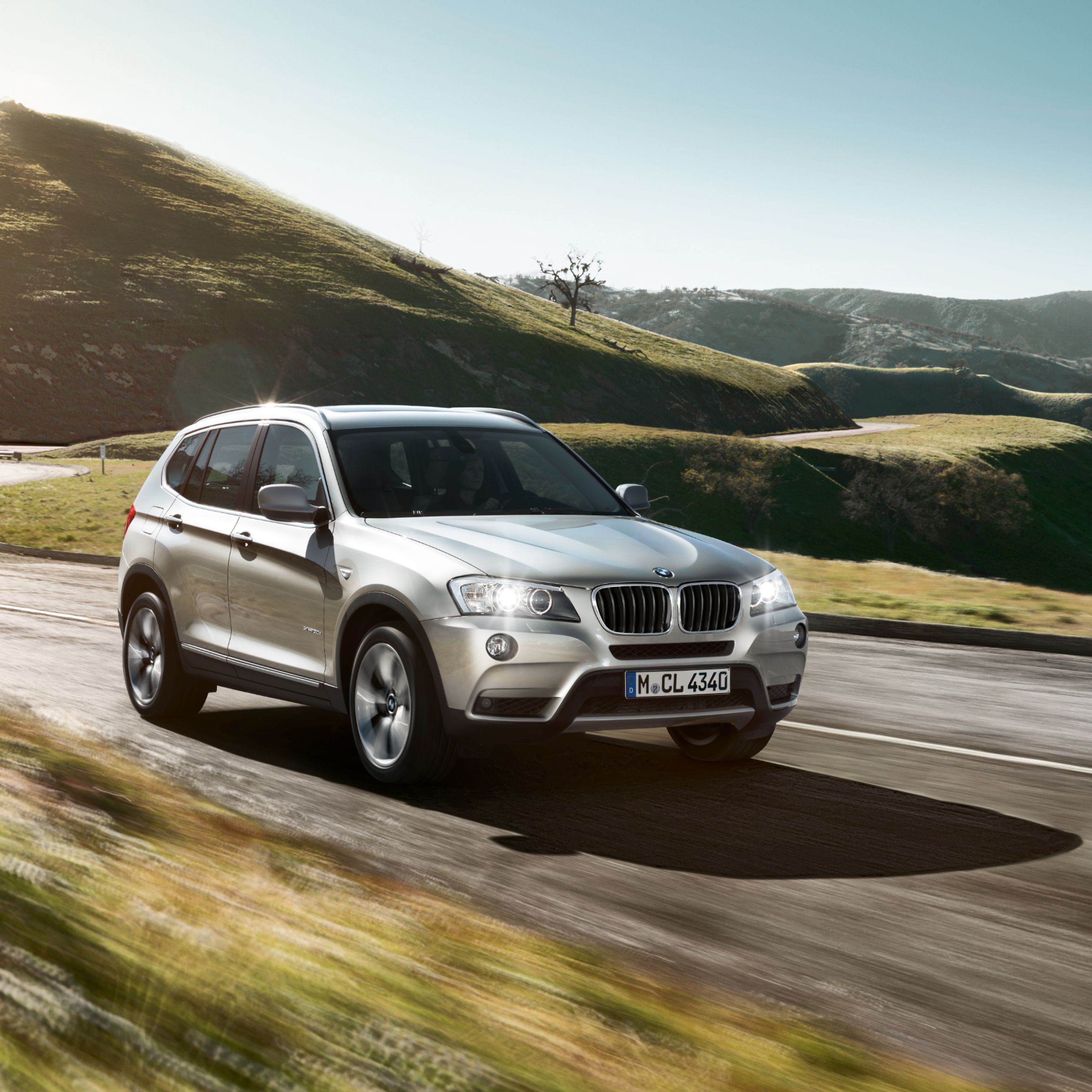 BMW X3 F25 SUV driving quickly on a serpentine road in the middle of the mountains