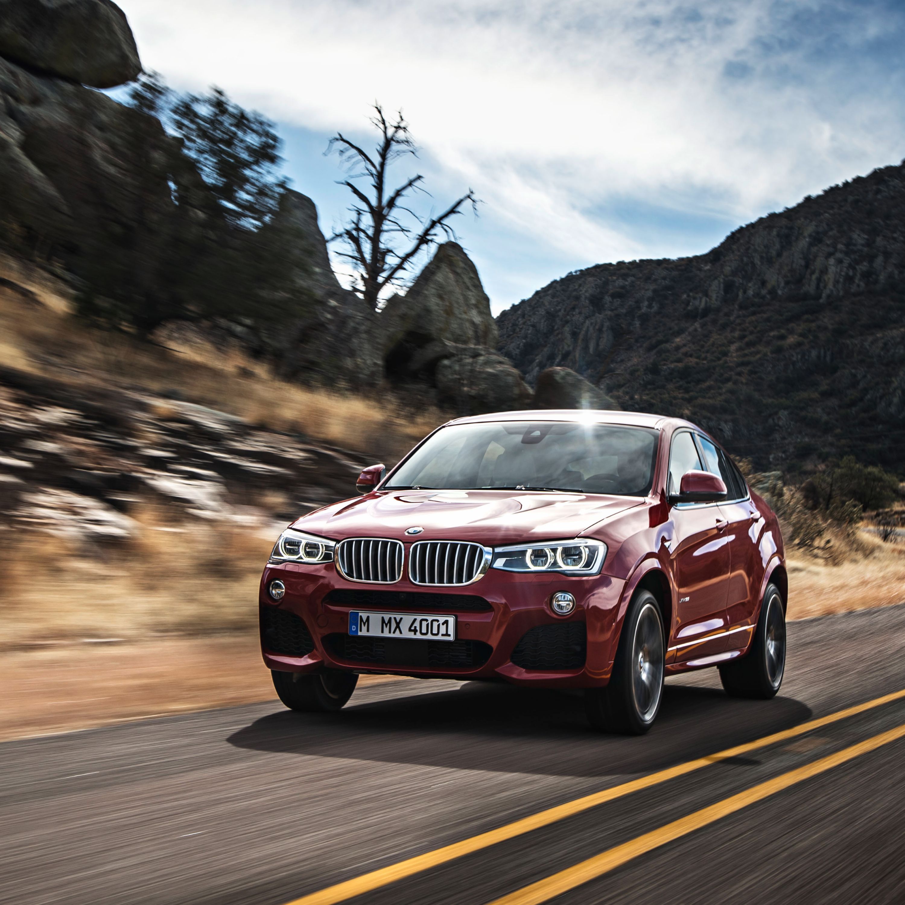 BMW X4 F26 SUV driving on a country rode through an American rocky mountain area