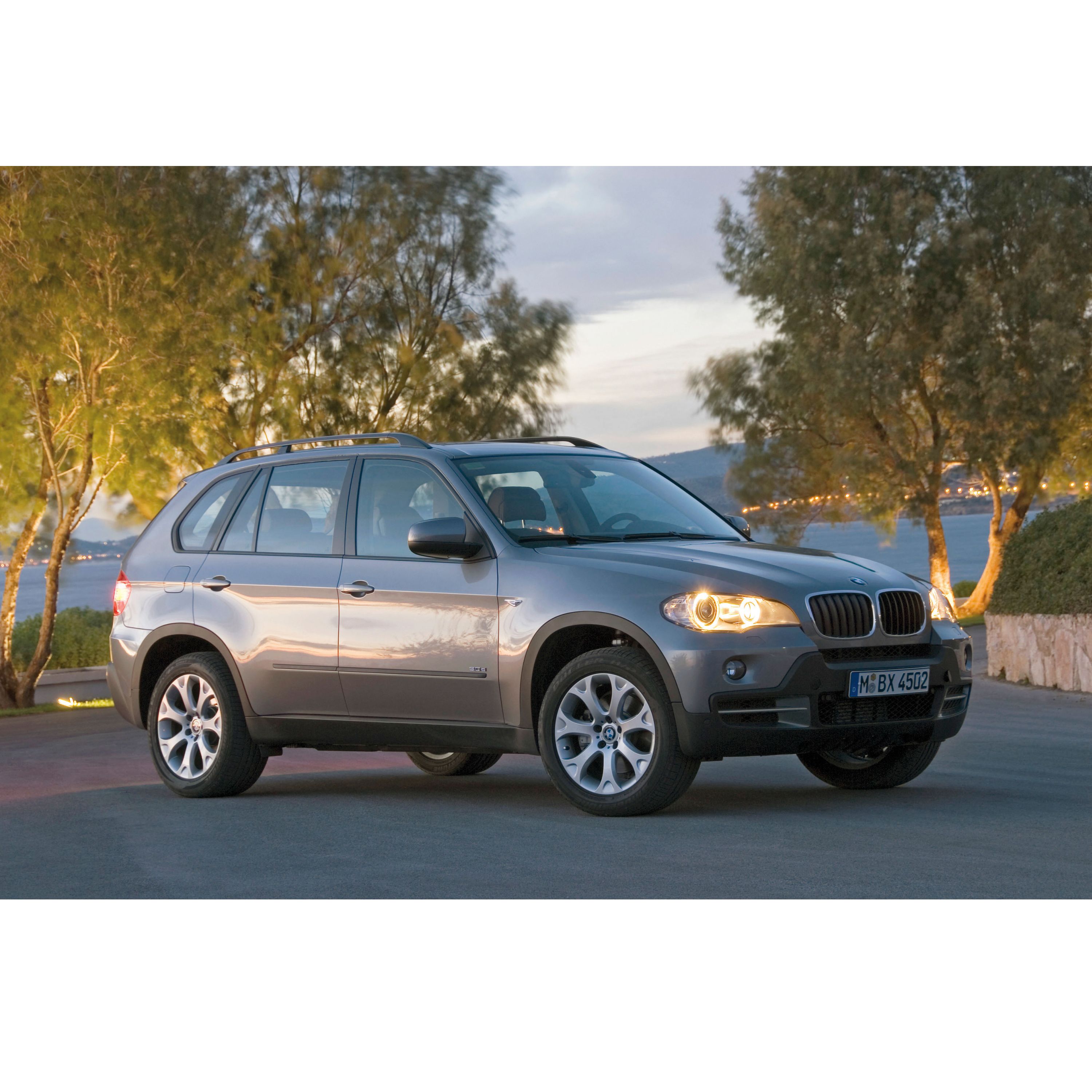 BMW X5 E70 SUV parked in front of a panoramic mountain lake