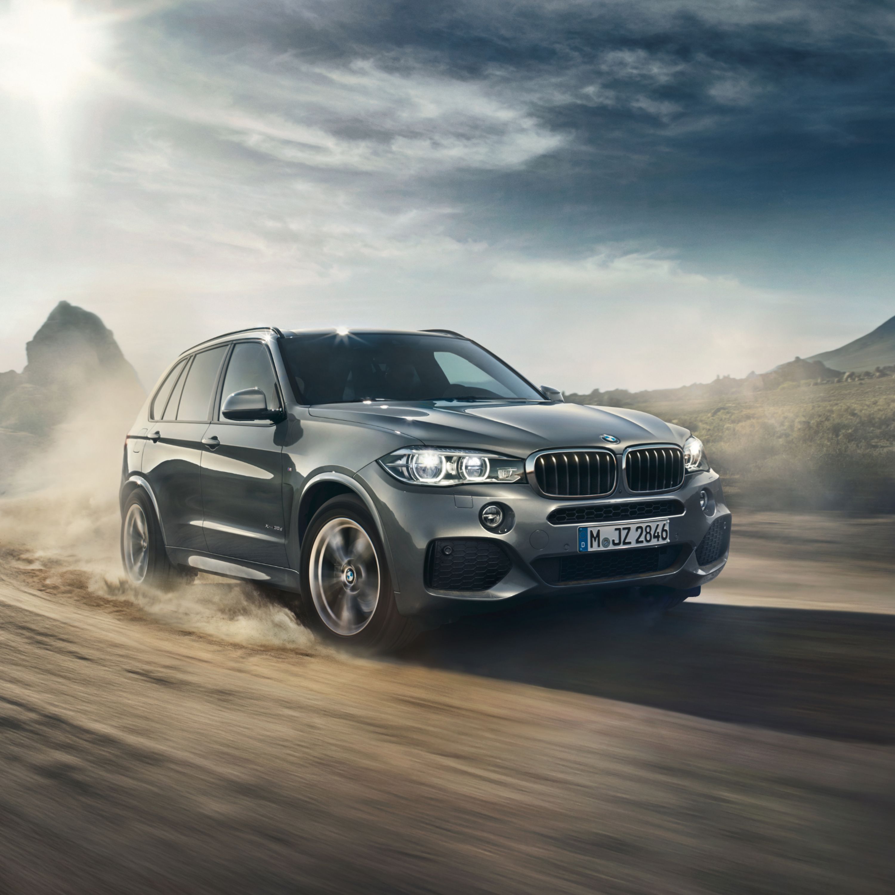 BMW X5 F15 SUV with a dust trail behind it on a track in the wilderness