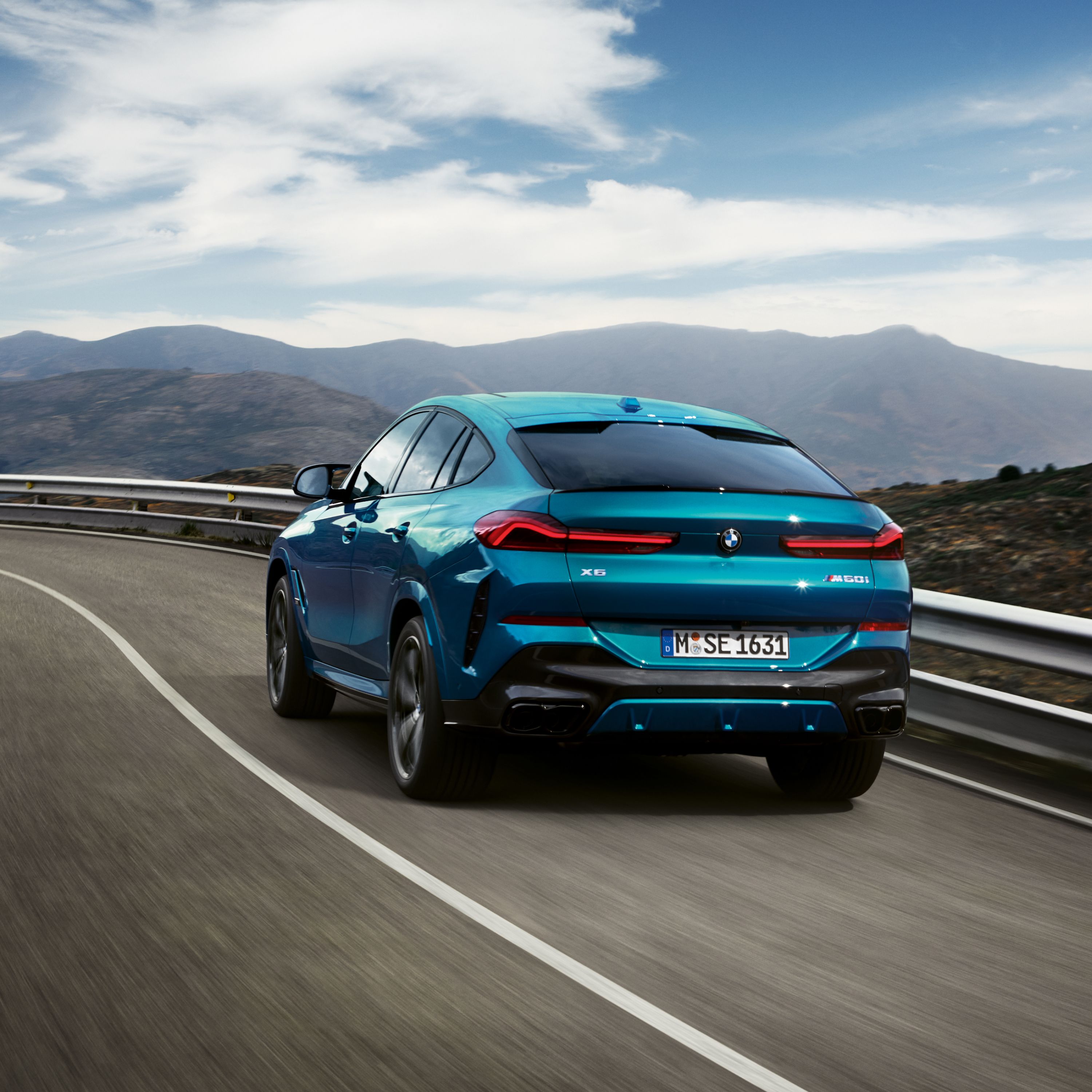 BMW X6 G06 SUV on a winding mountain road with a steep slope to the right and mountain panorama