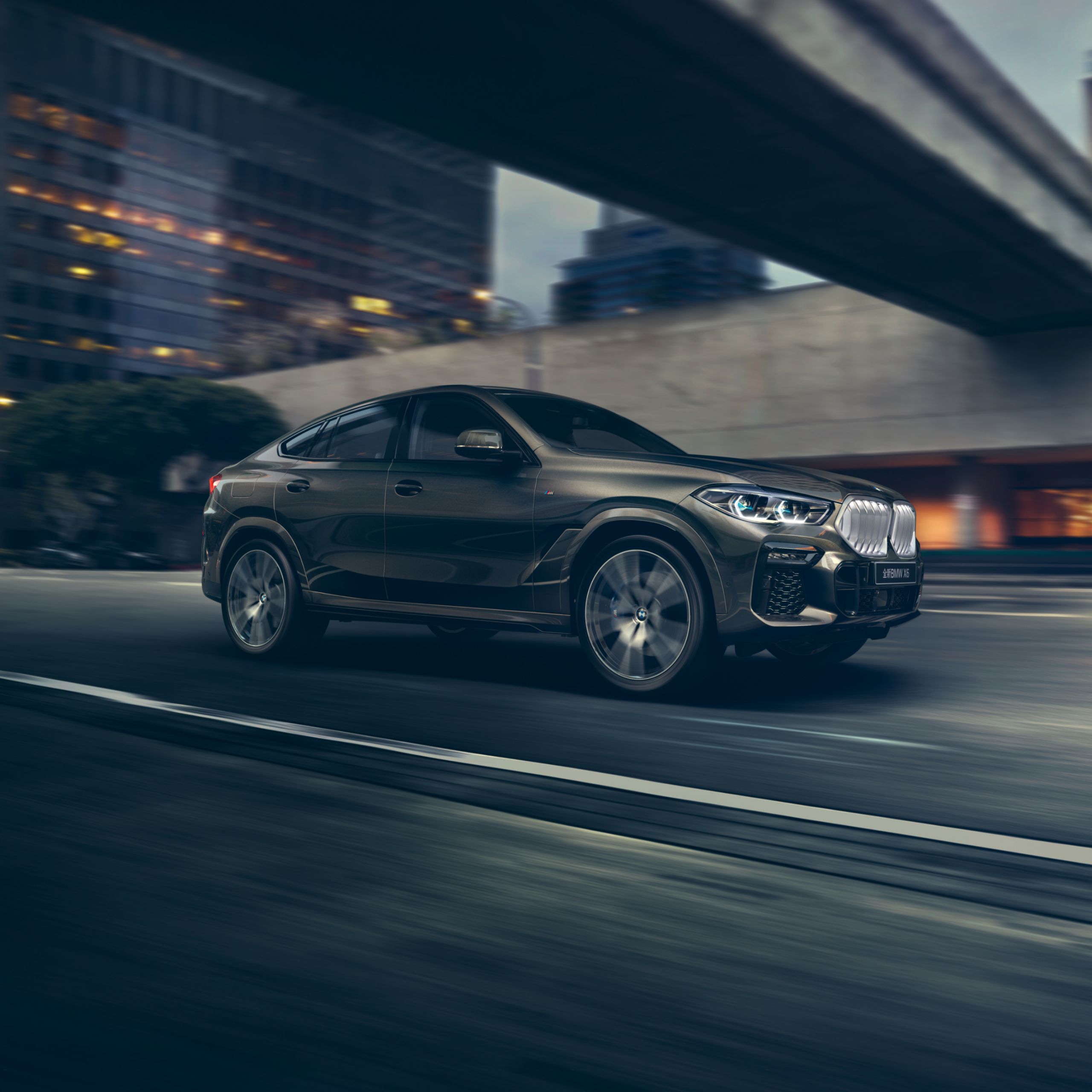 BMW X6 G06 SUV on an inner-city highway at night with illuminated buildings in the background