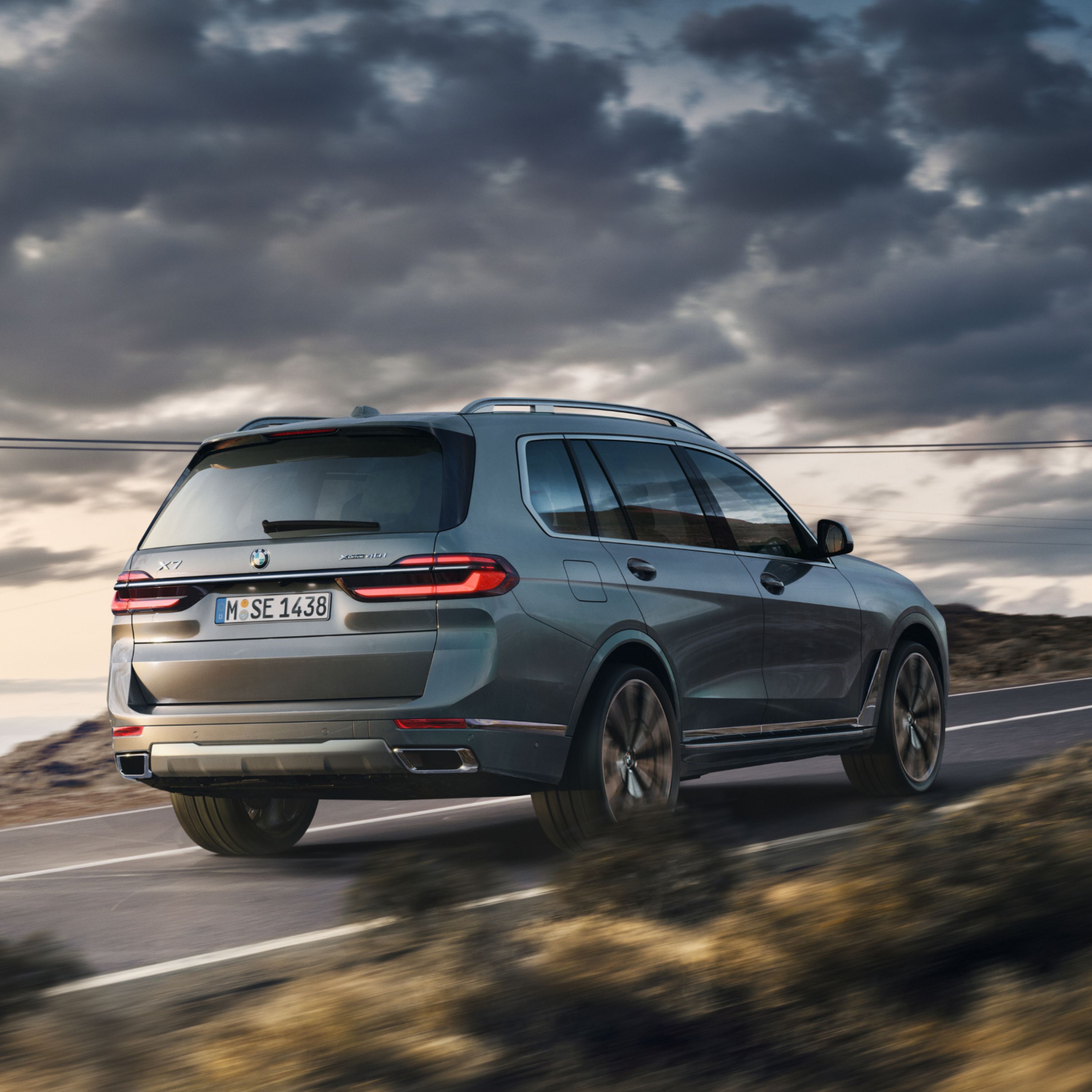 BMW X7 G07 SUV auf einer mediterranen Küstenstraße mit aufziehenden Gewitterwolken am Himmel