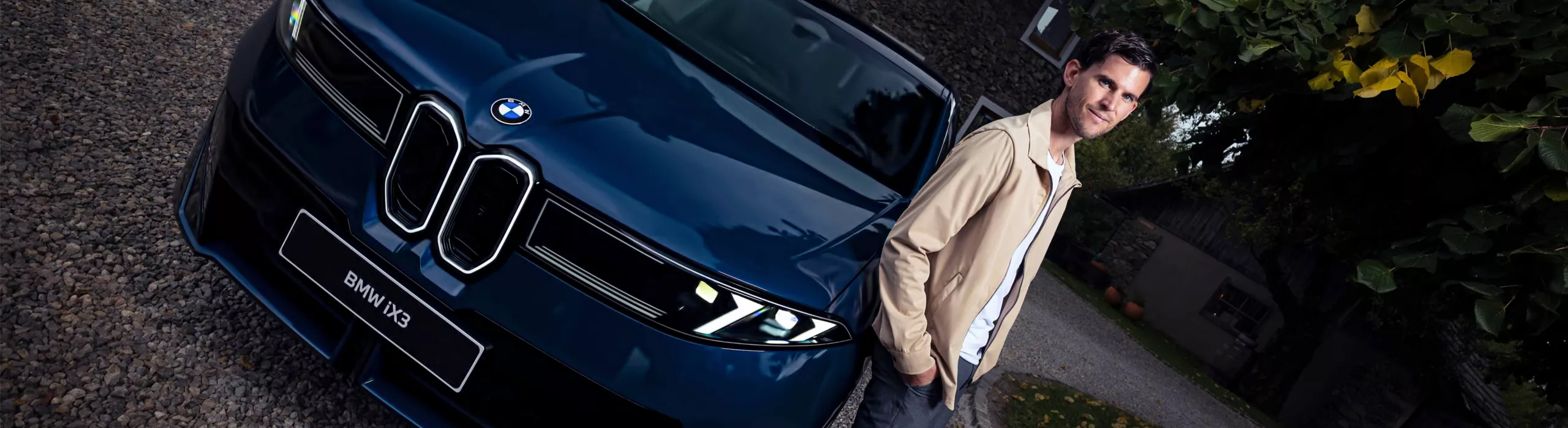 BMW Events - Dominic Thiem steht neben einem dunkelblauen BMW iX3 (NA5)