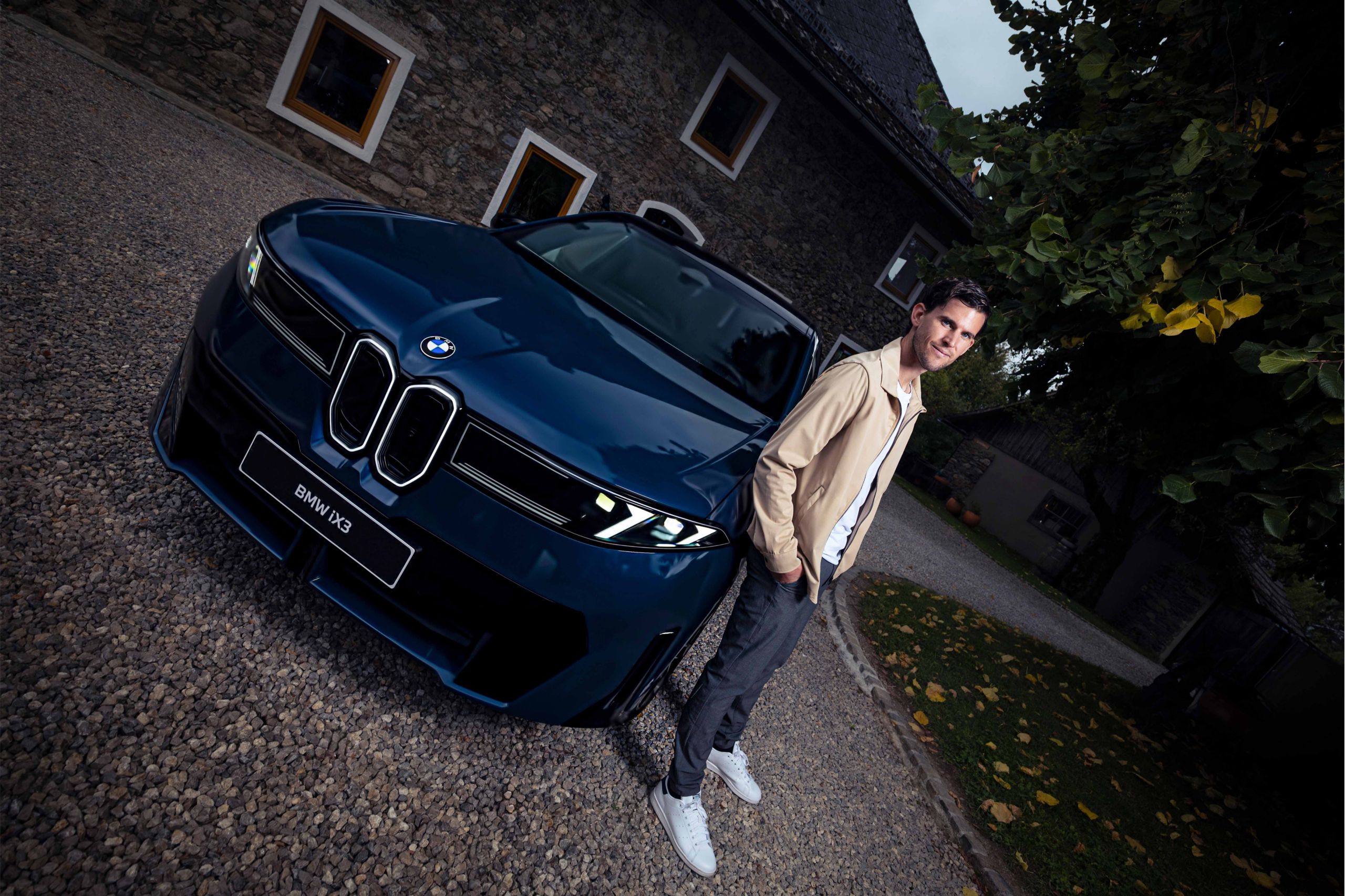 BMW Events - Dominic Thiem steht neben einem dunkelblauen BMW iX3 (NA5)