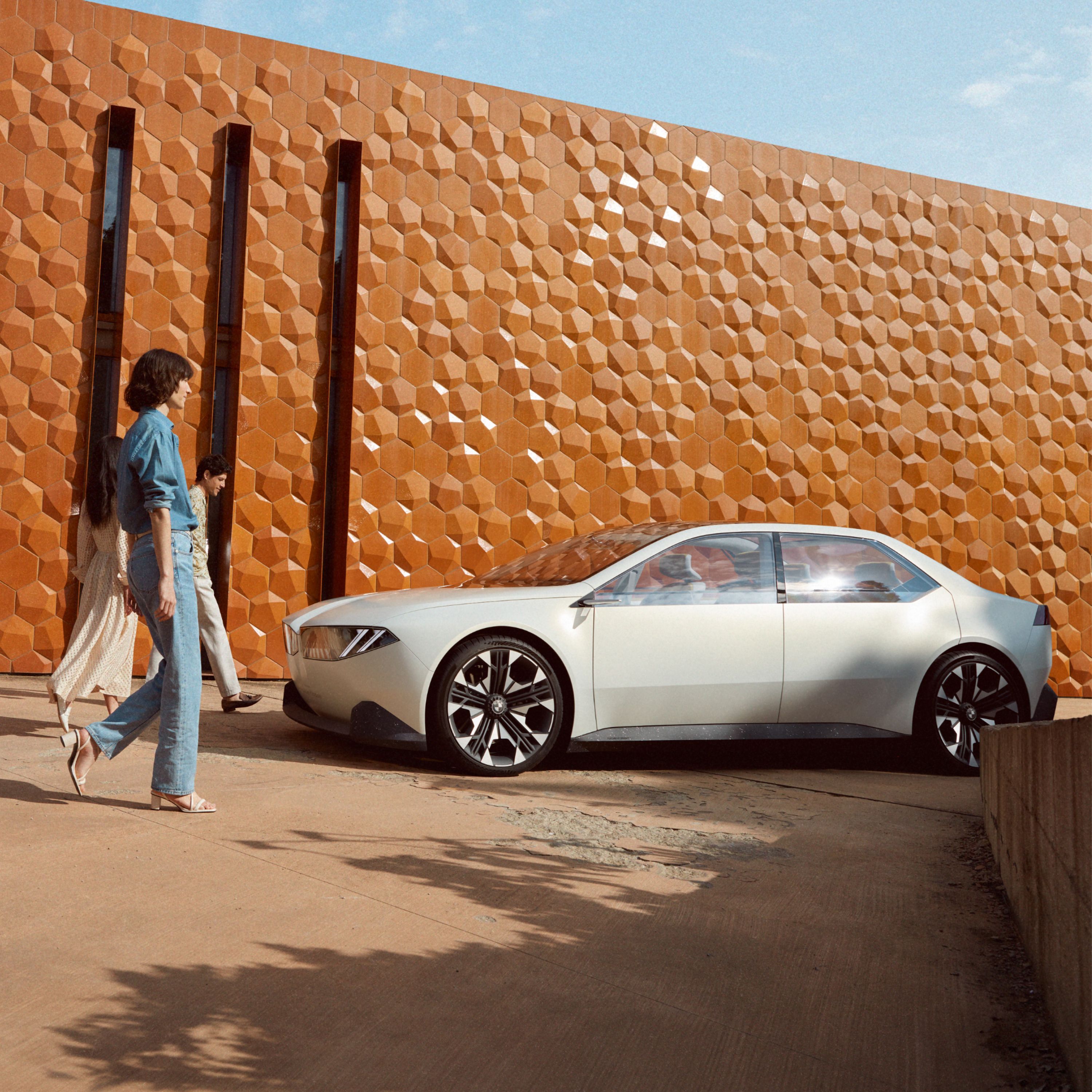 2023 BMW 비전 뉴 클래스 컨셉카 외부 4/5 측면뷰, 벽 앞에 주차, 여성 모델 1명
