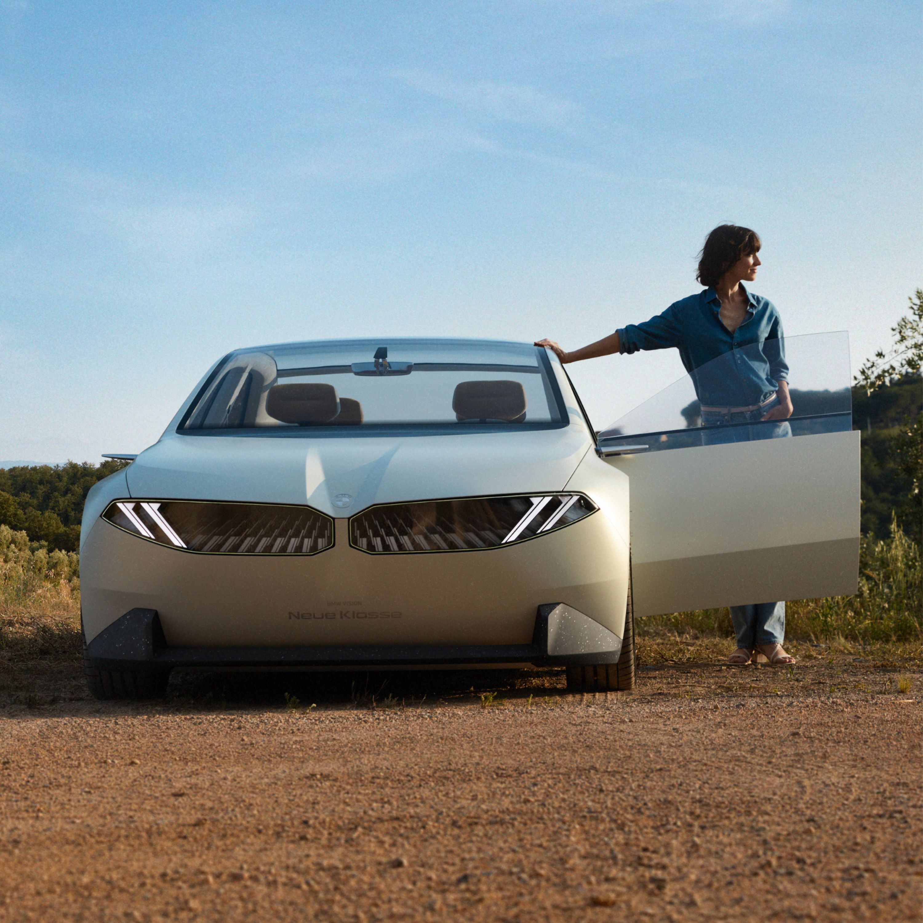 BMW Vision Neue Klasse, prototipo de 2023, exterior, vista frontal, aparcado en el desierto, puerta abierta, con mujer