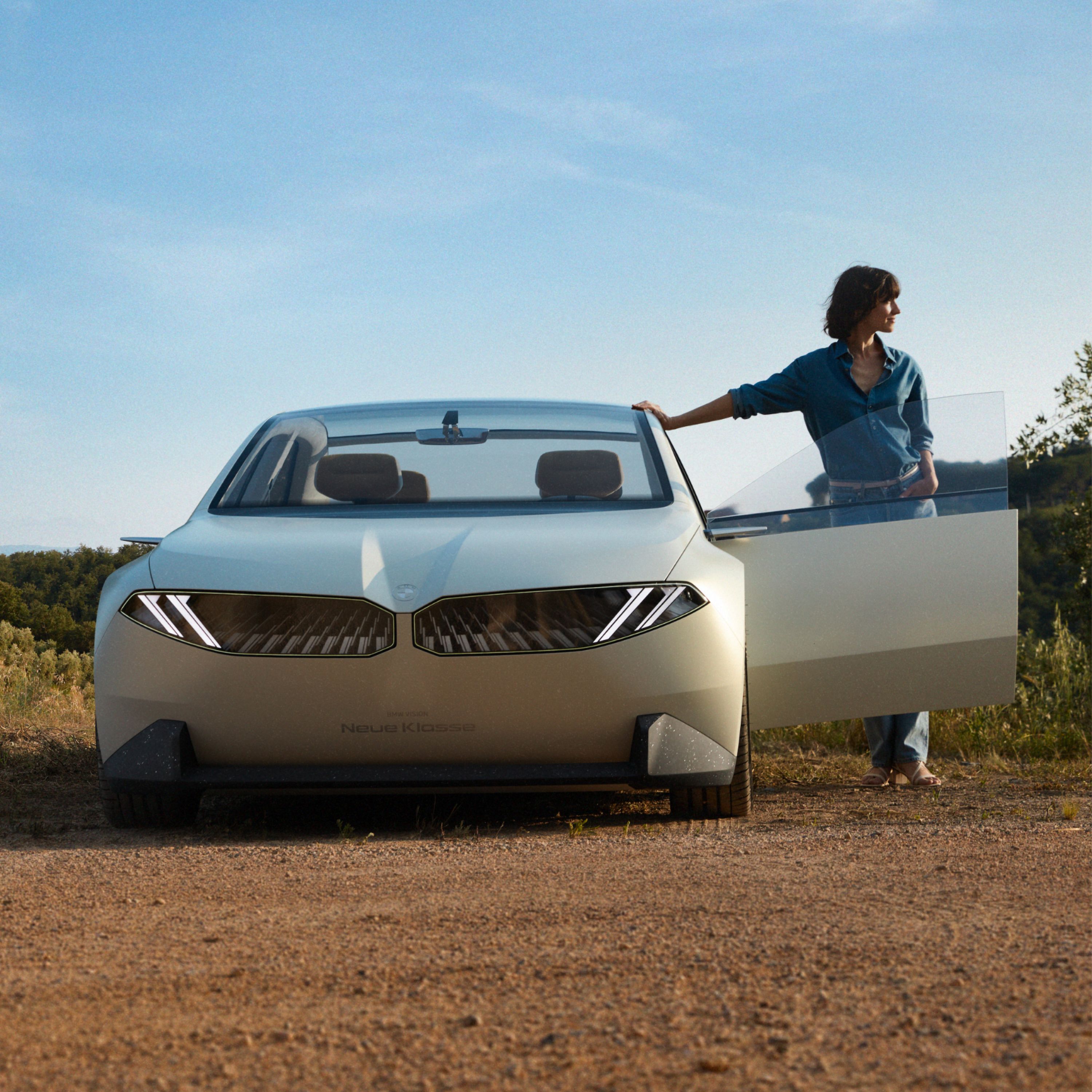 BMW Vision Neue Klasse Konceptno vozilo 2023, vanjština, pogled sprijeda, parkiran u pustinji, otvorena vrata, sa ženom