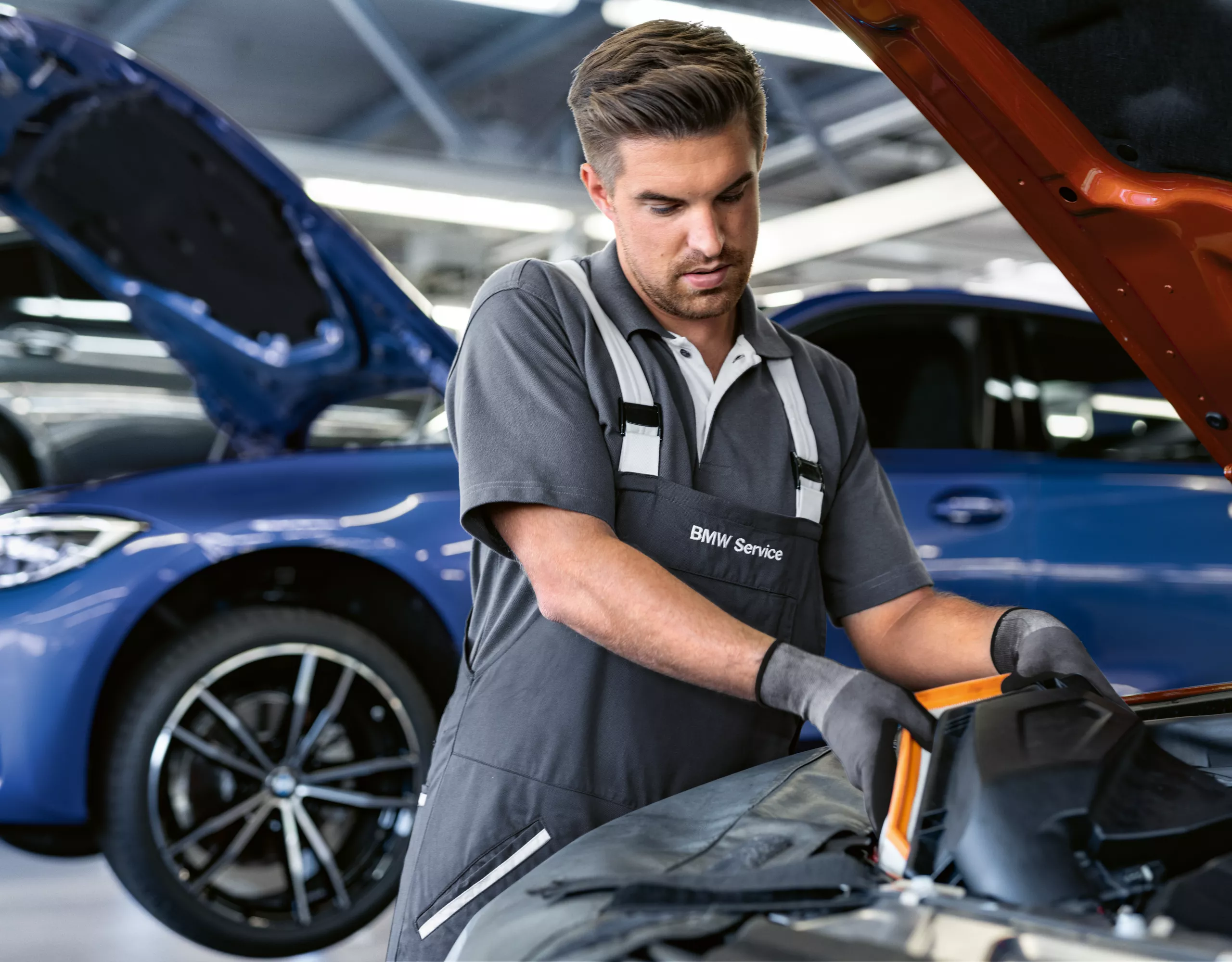 BMW Servicetechniker arbeitet in einer Werkstatt an einem geöffneten Motorraum