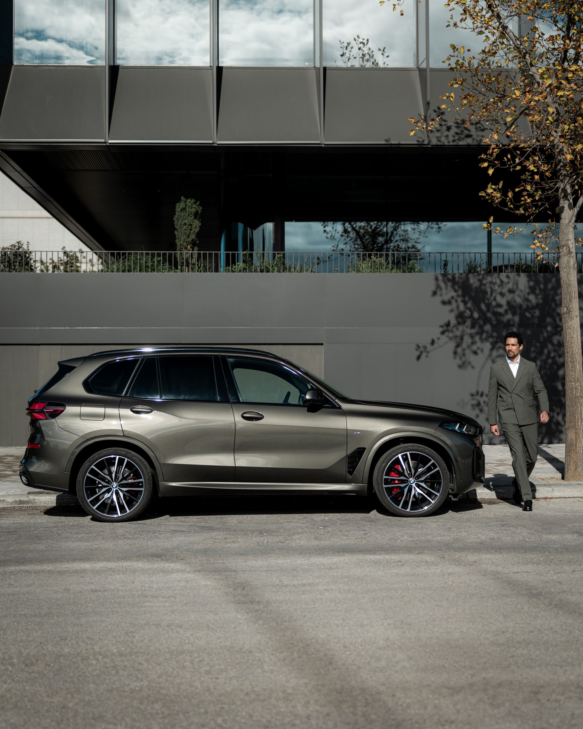 BMW X5 parcat pe marginea unei străzi într-un cadru urban modern, surprins din profil