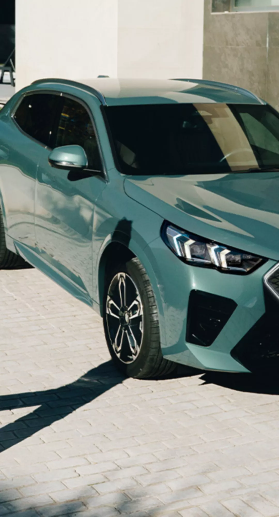  BMW iX2 parcat lângă o casă modernă, cu o persoană în appropriere