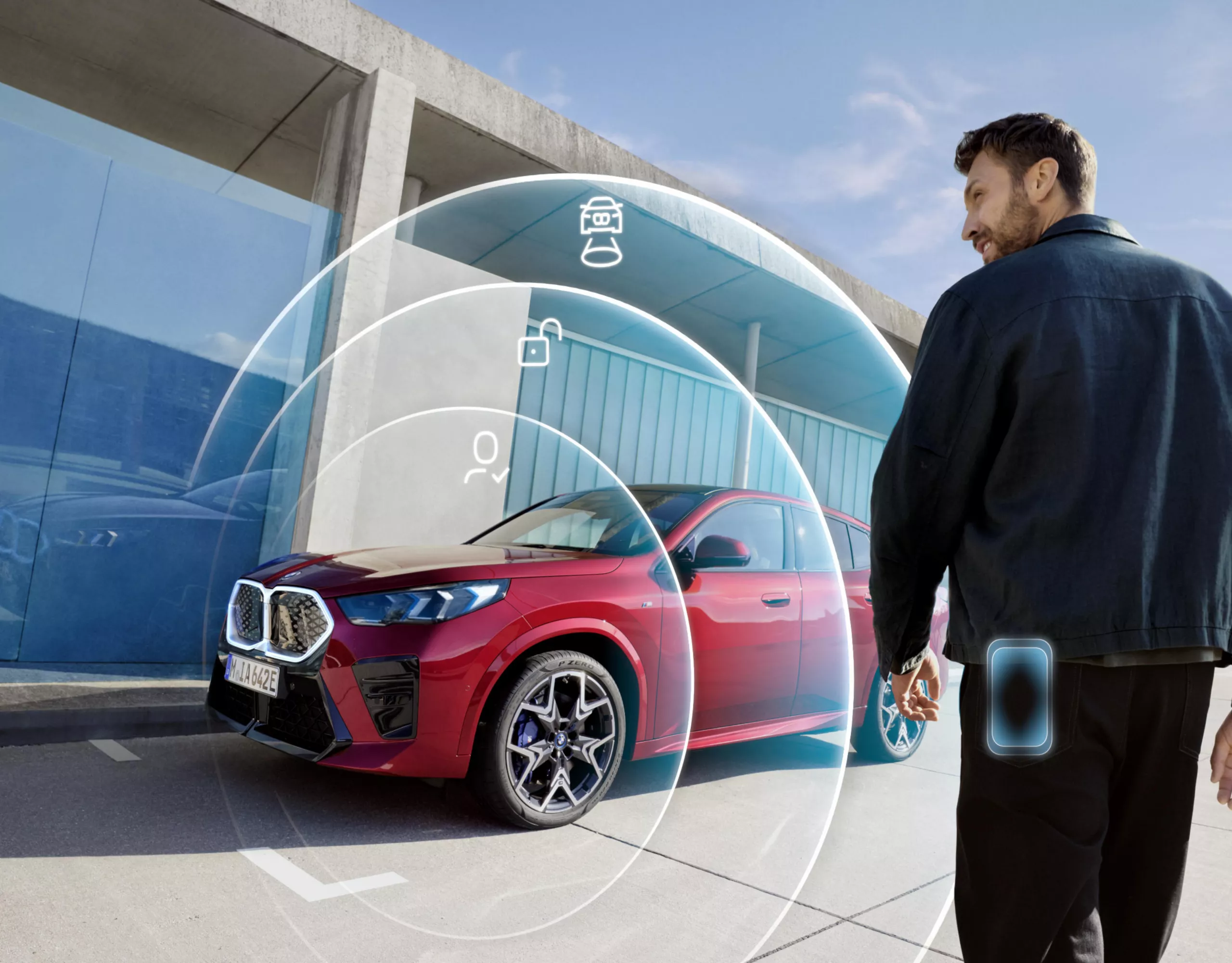 Ein Mann steht vor einem BMW X2. Um das Auto sind die 3 Phasen des Digital Keys mit Willkommensbeleuchtung, Entriegelung und Starten des Motors eingeblendet
