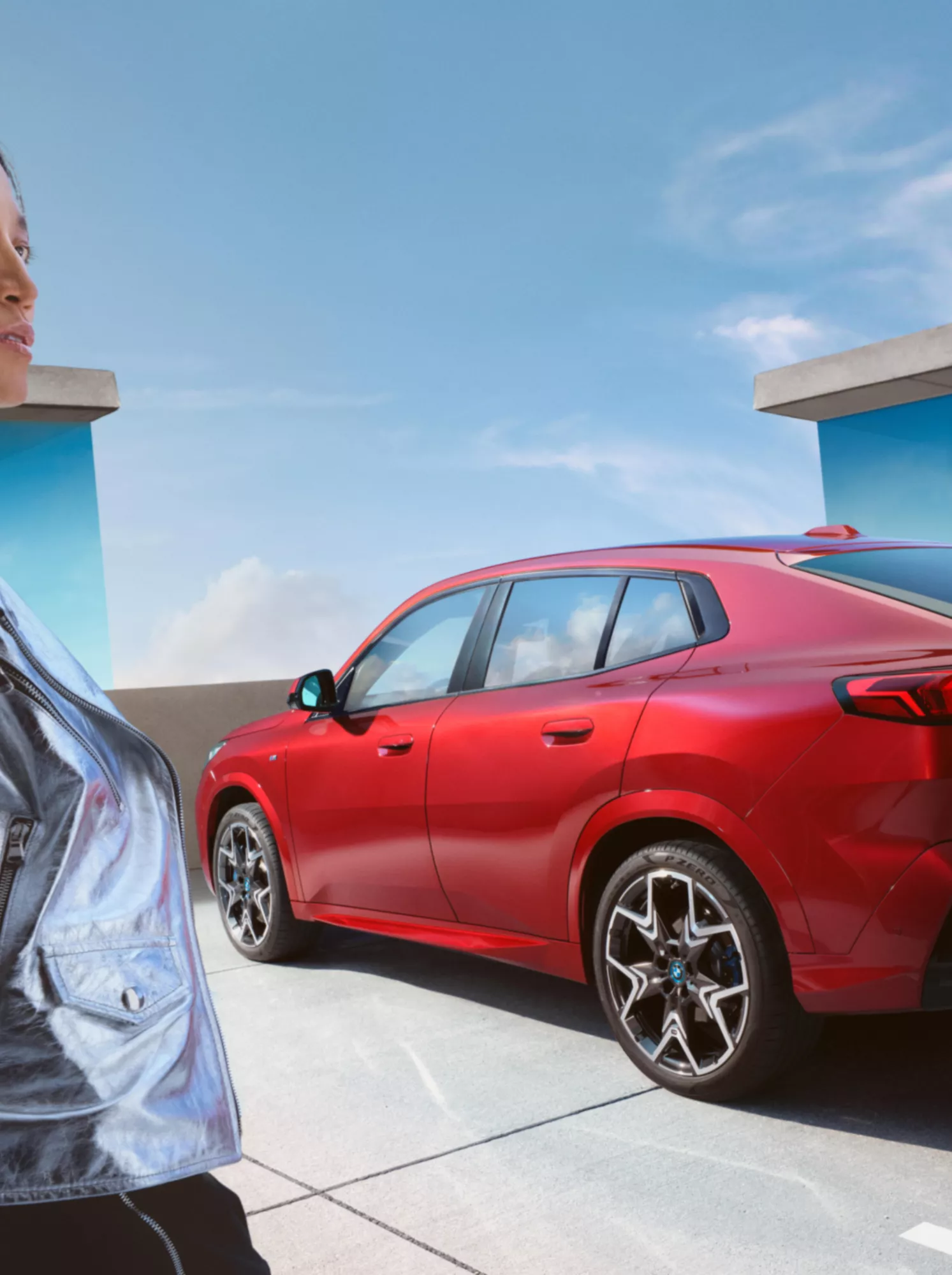 Eine Frau steht vor einem vollelektrischen BMW iX2