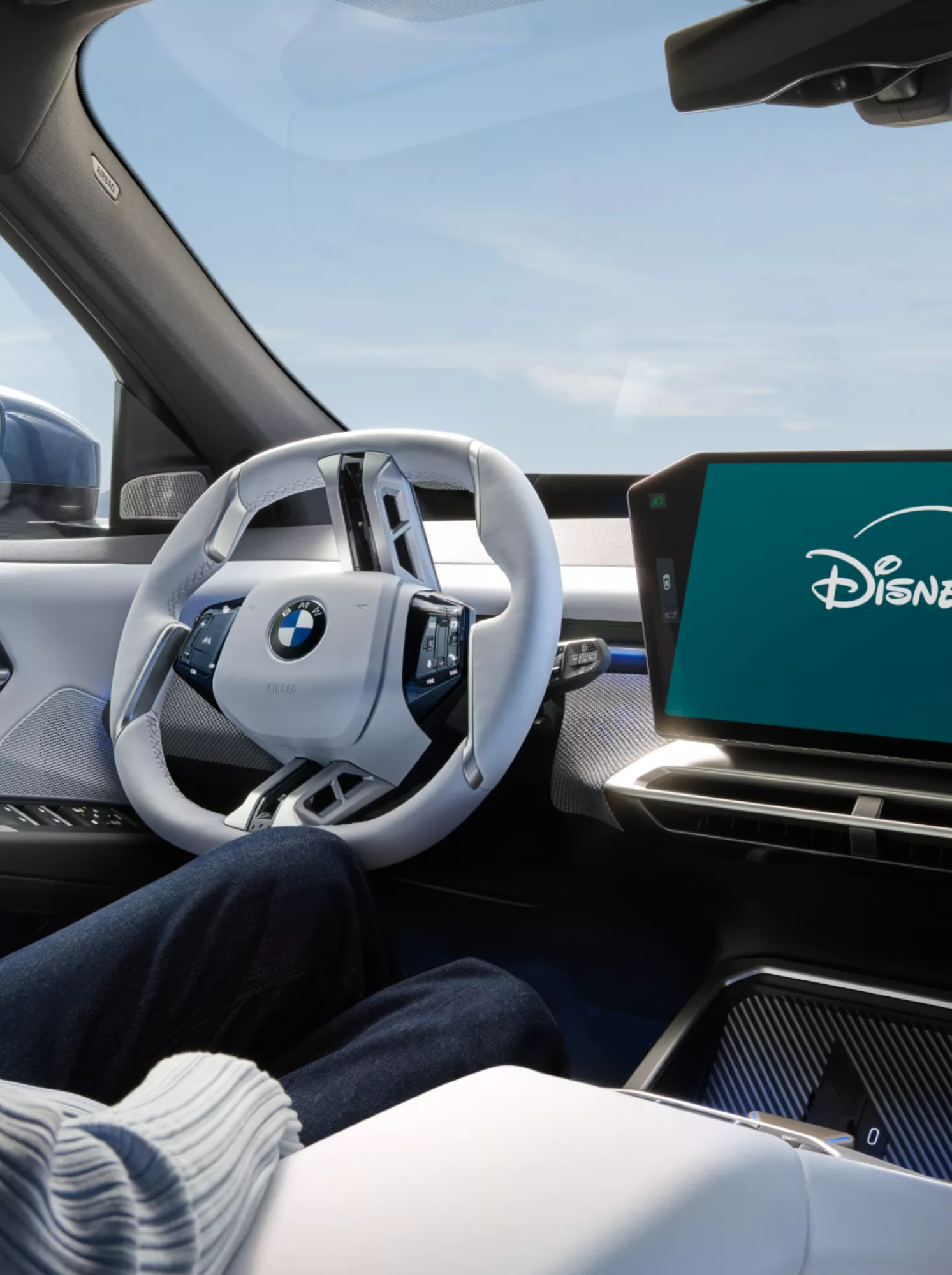 A woman is watching the Disney+ streaming portfolio inside a parked BMW from the driver’s seat