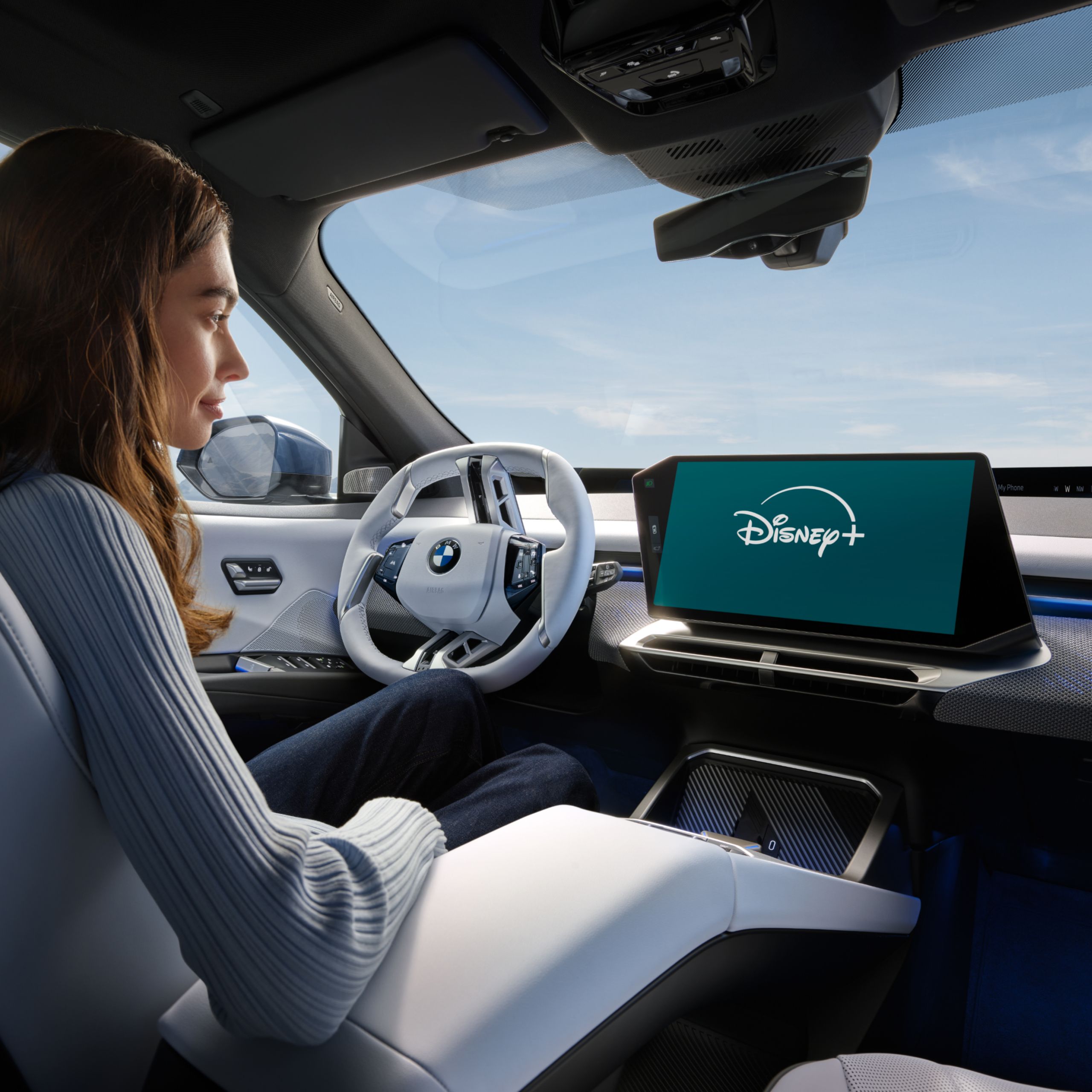 A woman is watching Disney+ streaming inside a parked BMW from the driver’s seat