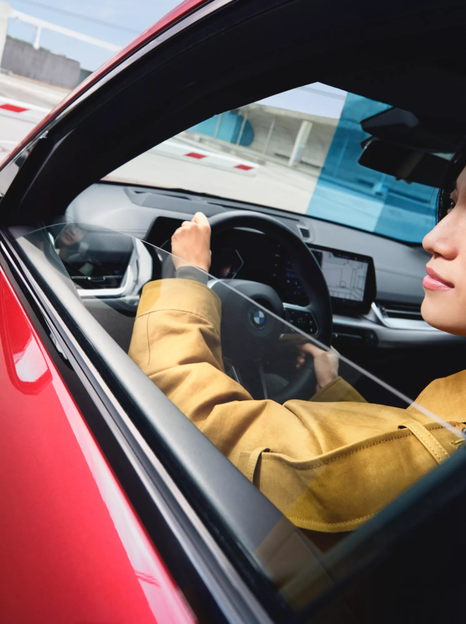 Person am Steuer eines BMW mit geöffnetem Seitenfenster, das bei Einfahrt in eine Parkgarage automatisch geöffnet wird