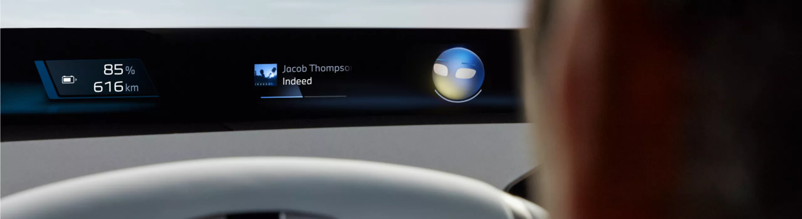 Person sitzt auf dem Fahrersitz im BMW und schaut auf das zentrale Display mit dem BMW Intelligent Personal Assistant