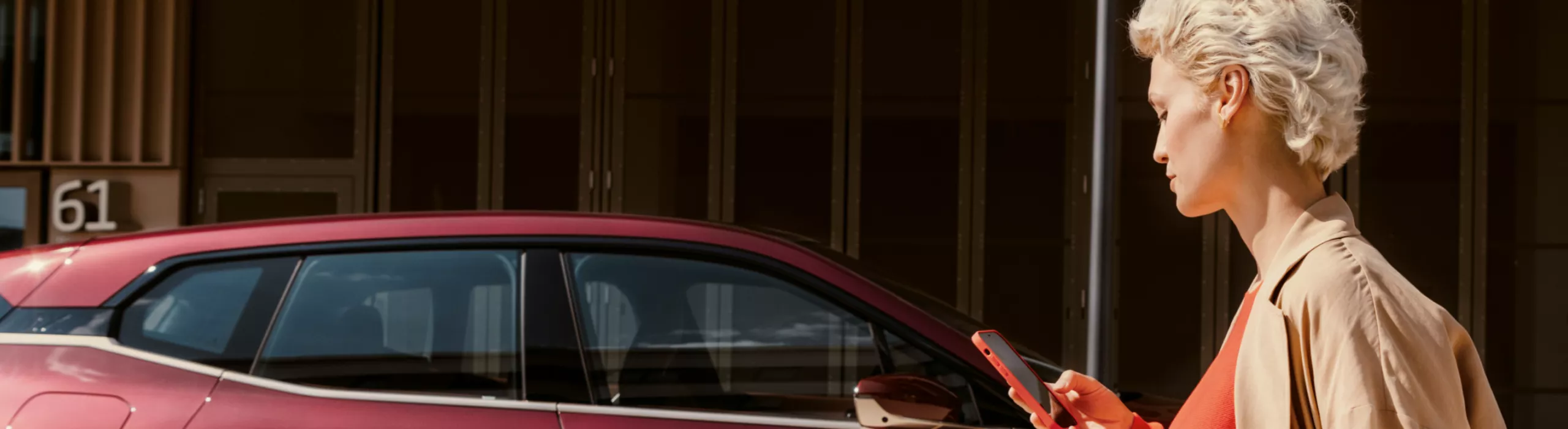 Man in front of BWW iX uses My BMW app on smartphone