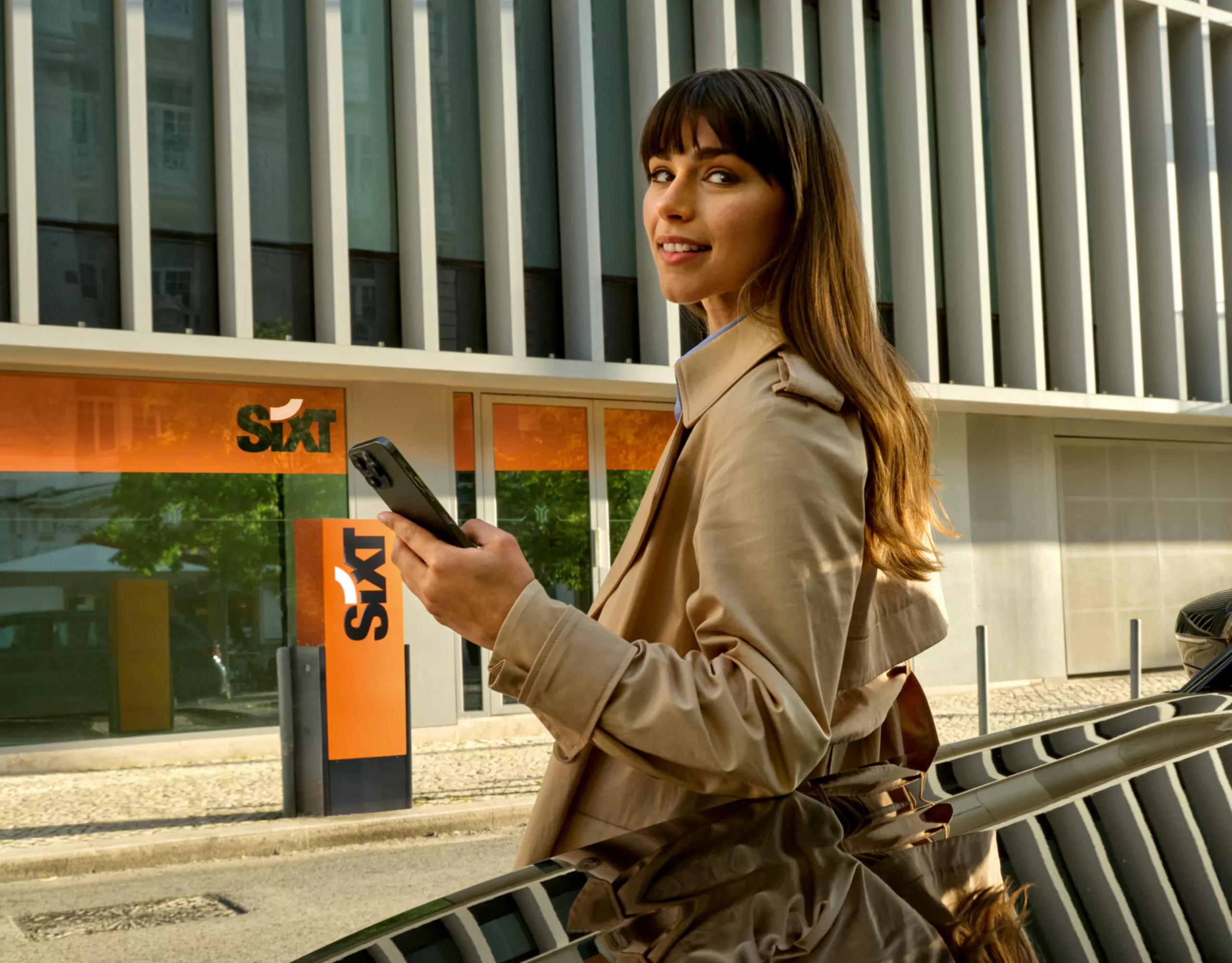 Person mit Smartphone neben BMW