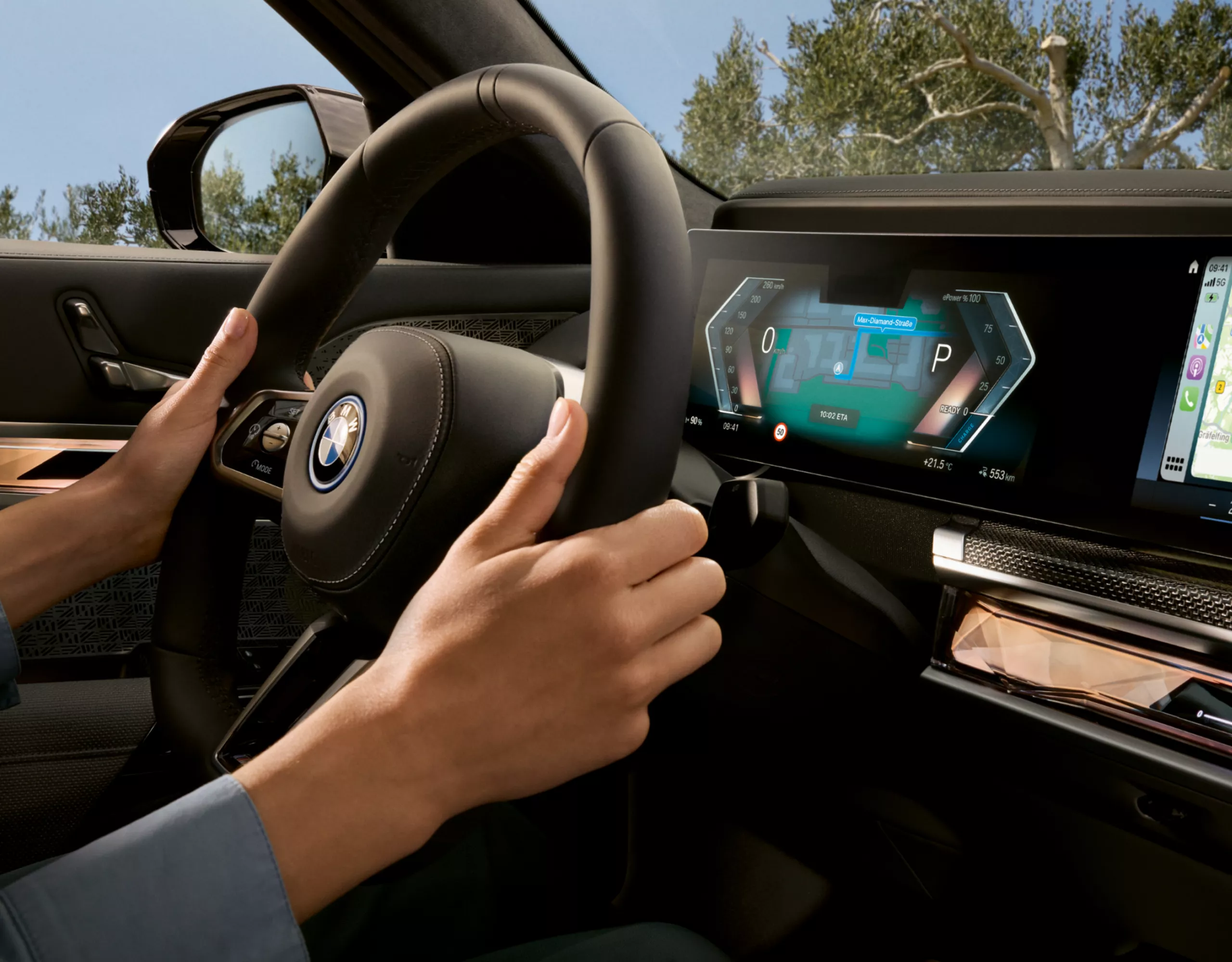 BMW Cockpit mit Händen am Lenkrad. Dahinter sichtbar das zentrale Display mit Anzeigen des Driving Assistant Plus