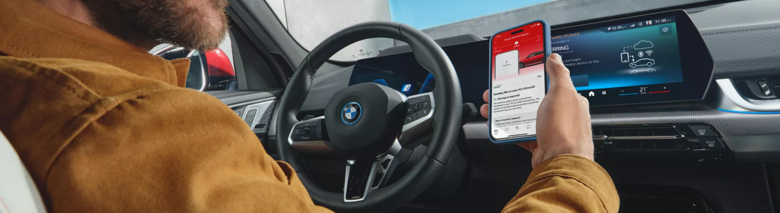 Person in BMW mit Smartphone beim Starten eines Software Updates
