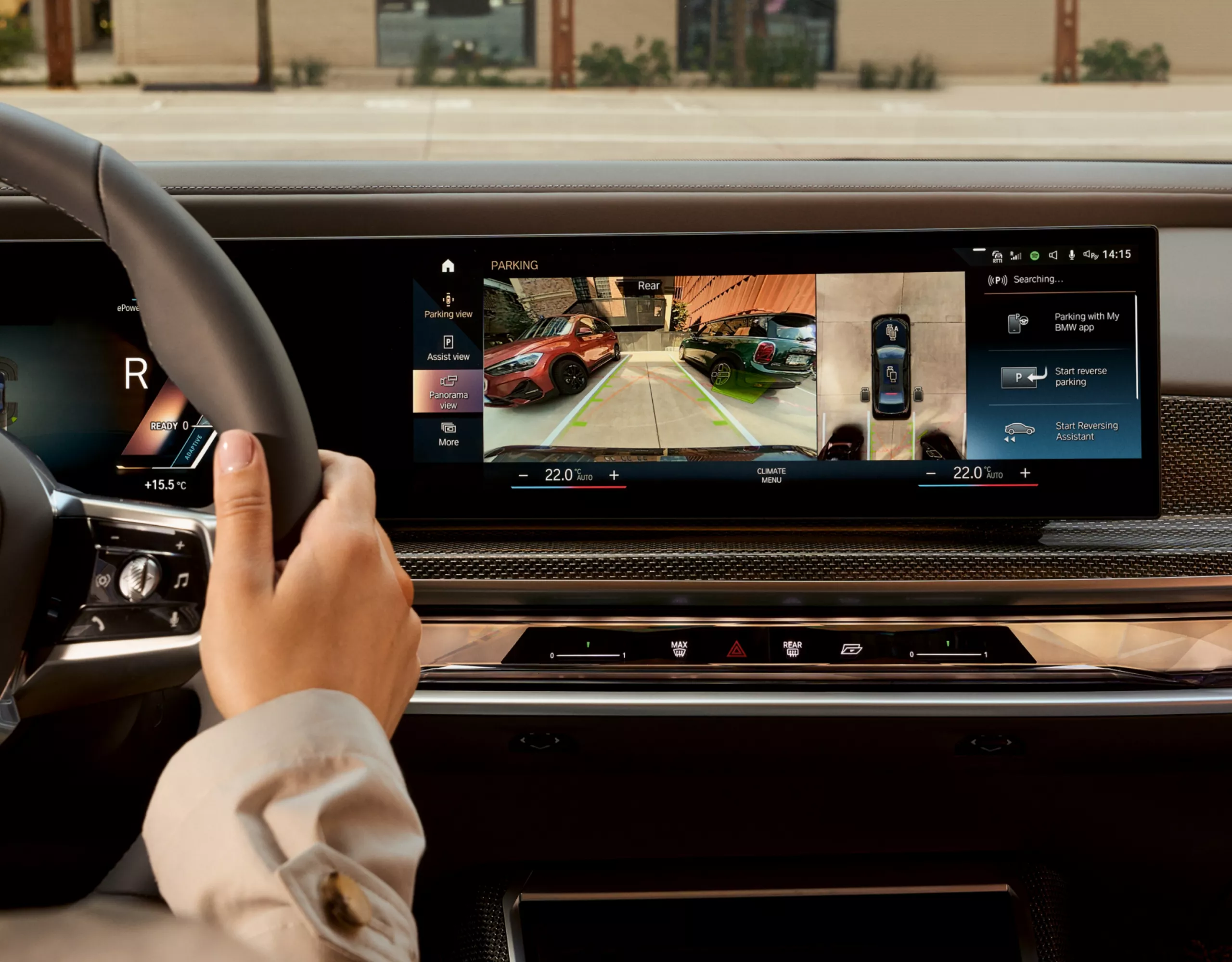 BMW cockpit with hand on steering wheel – display shows rear view camera view for improved parking and parking aid lines