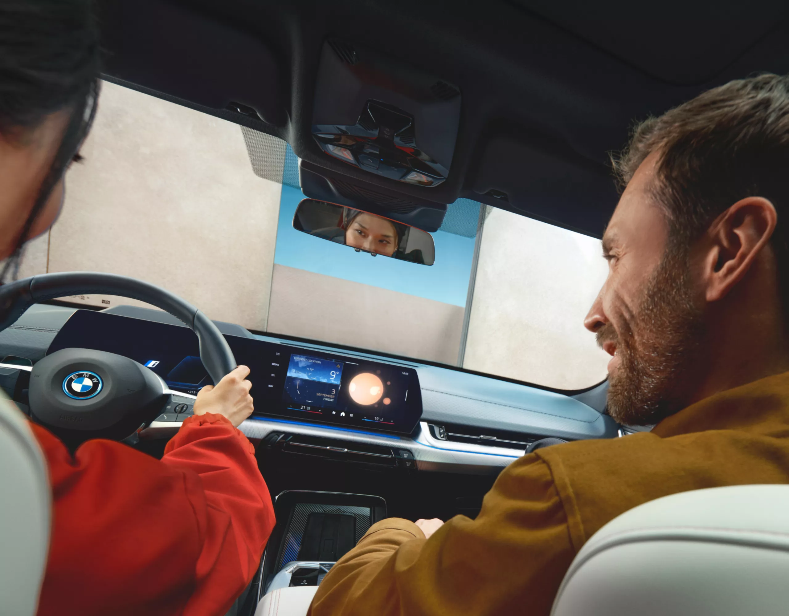 Personas en la cabina de un BMW hablan con el Intelligent Personal Assistant, que se visualiza en el display de control