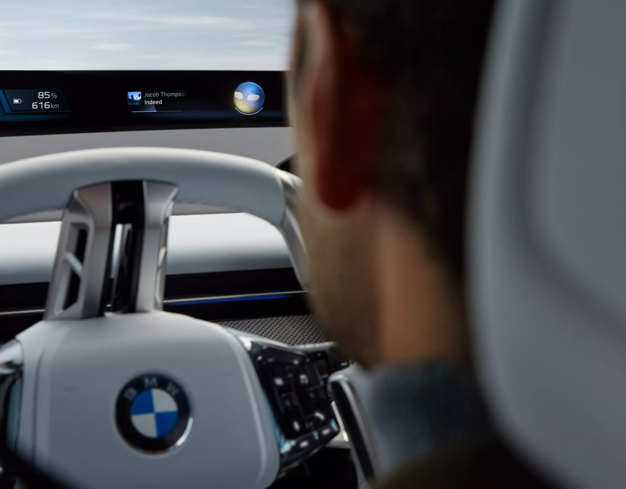 Personen im Cockpit eines BMW sprechen mit den Intelligent Personal Assistant, der im Fahrzeugdisplay visualisiert ist