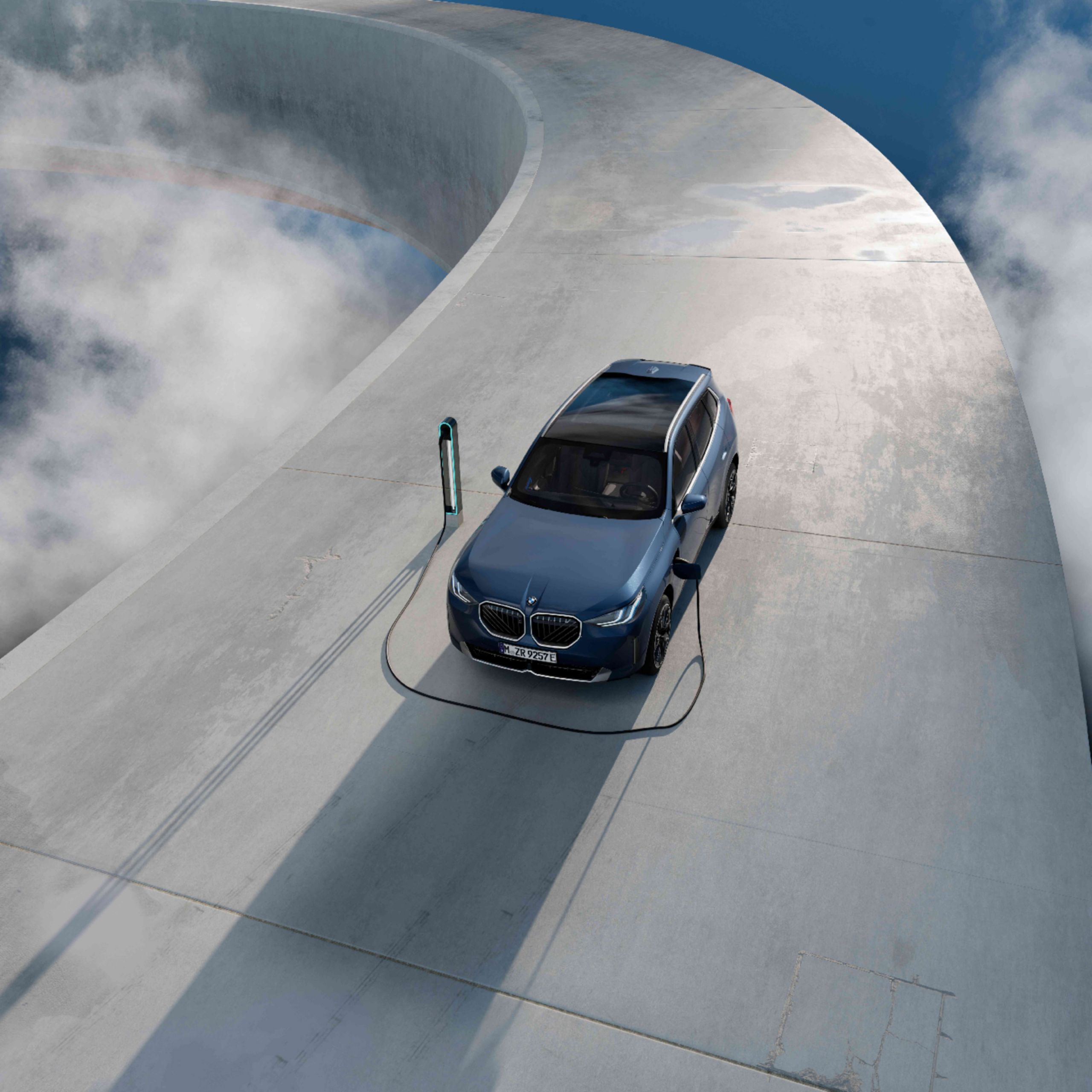 A BMW is charging at a charging station on a large concrete surface with clouds in the background