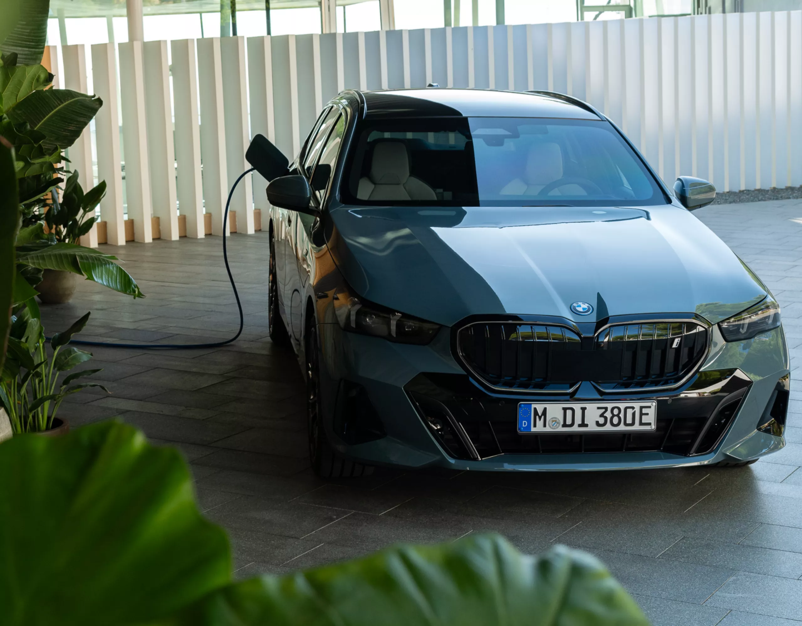 A fully electric BMW is being charged beneath a car port