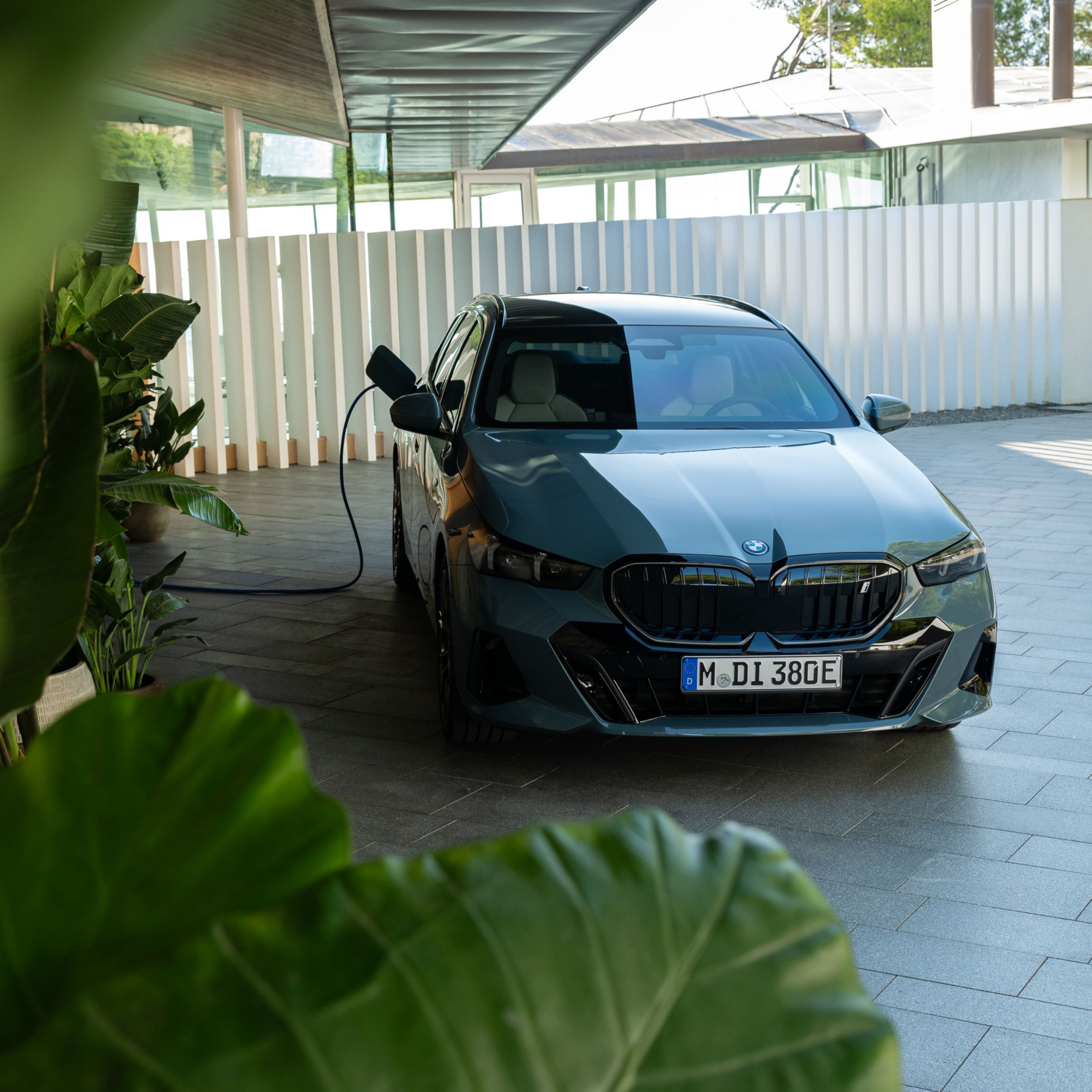 A fully electric BMW is being charged beneath a car port