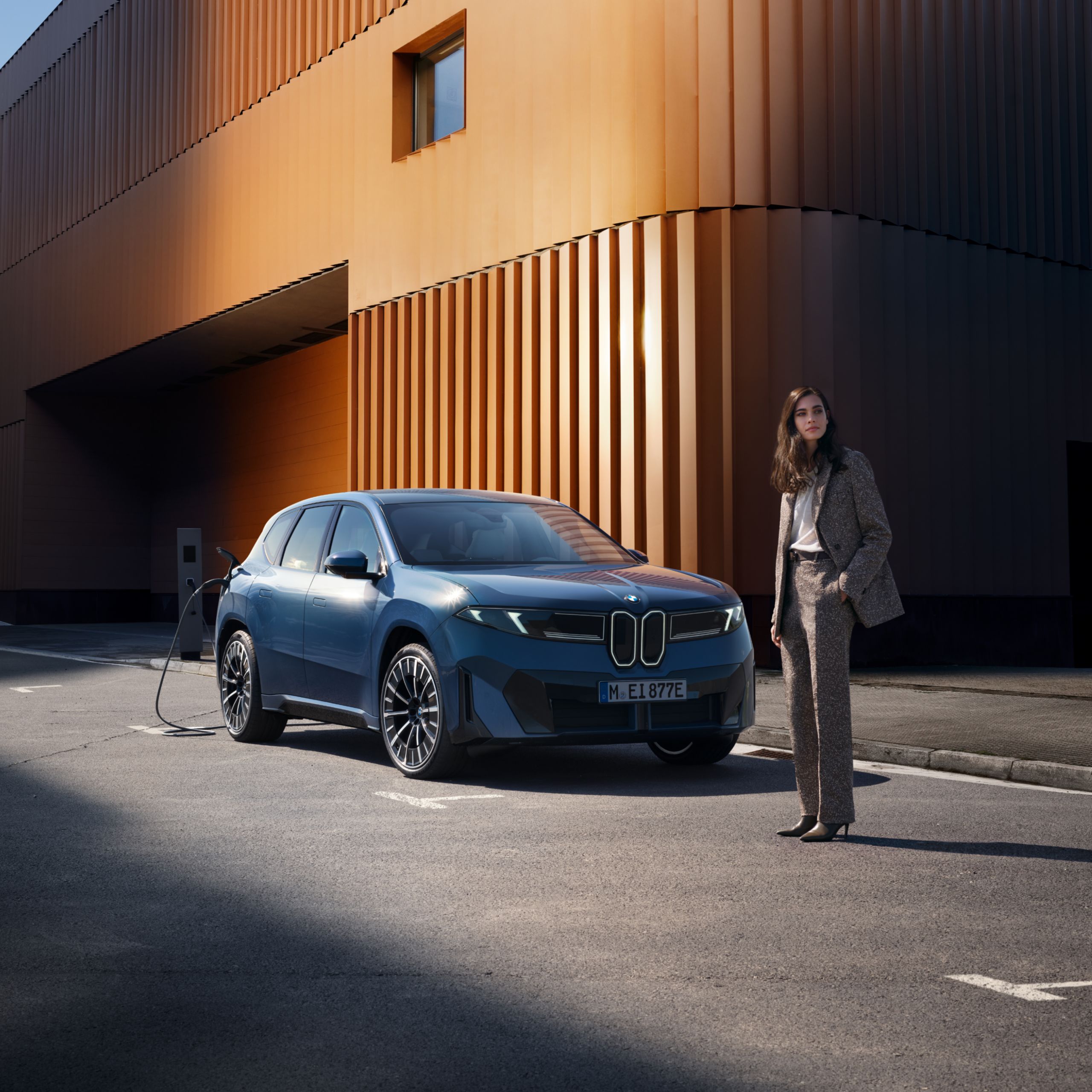 A fully electric BMW is being charged at a charging station on a surreal road