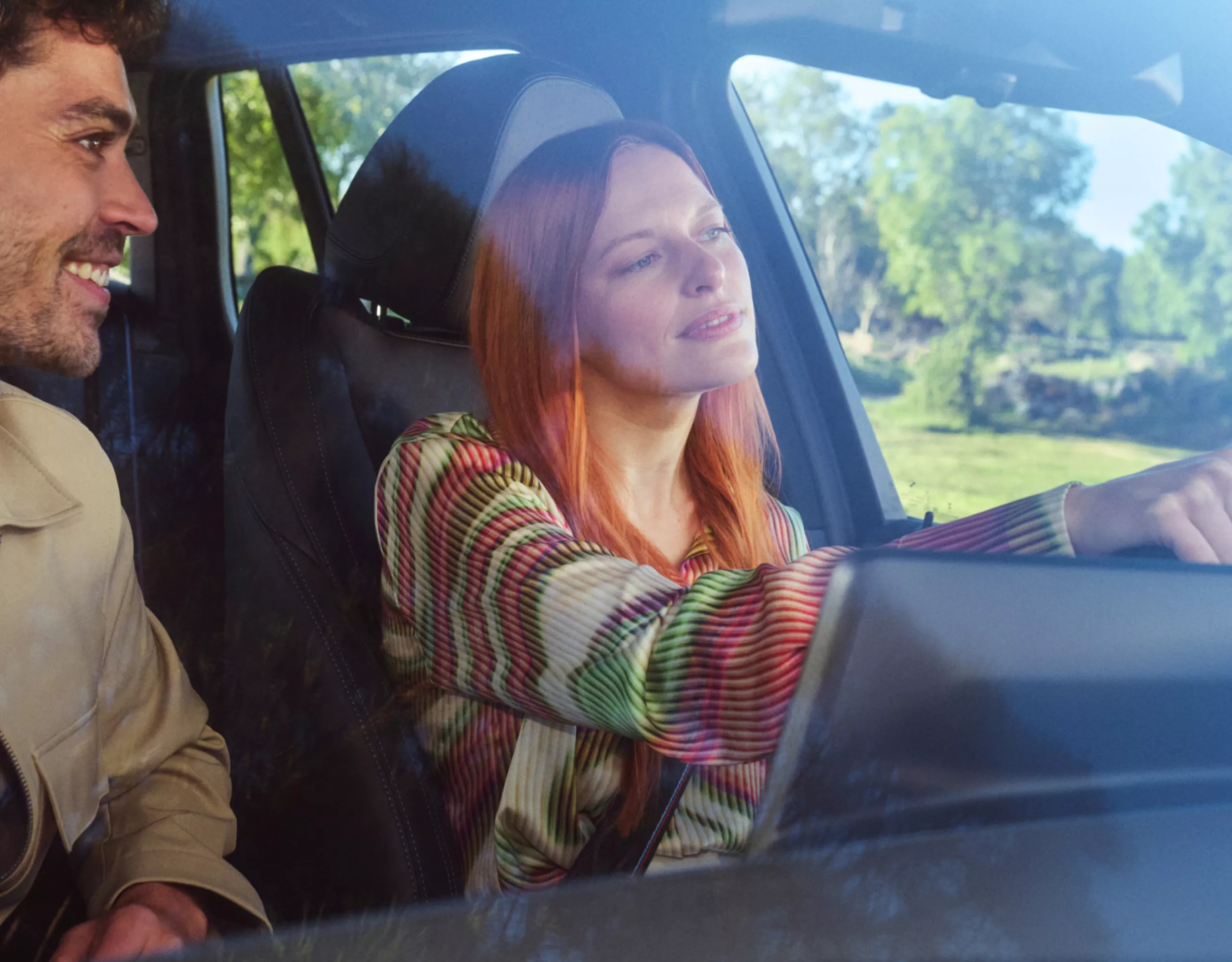 Two people are smiling happily while sitting in a BMW