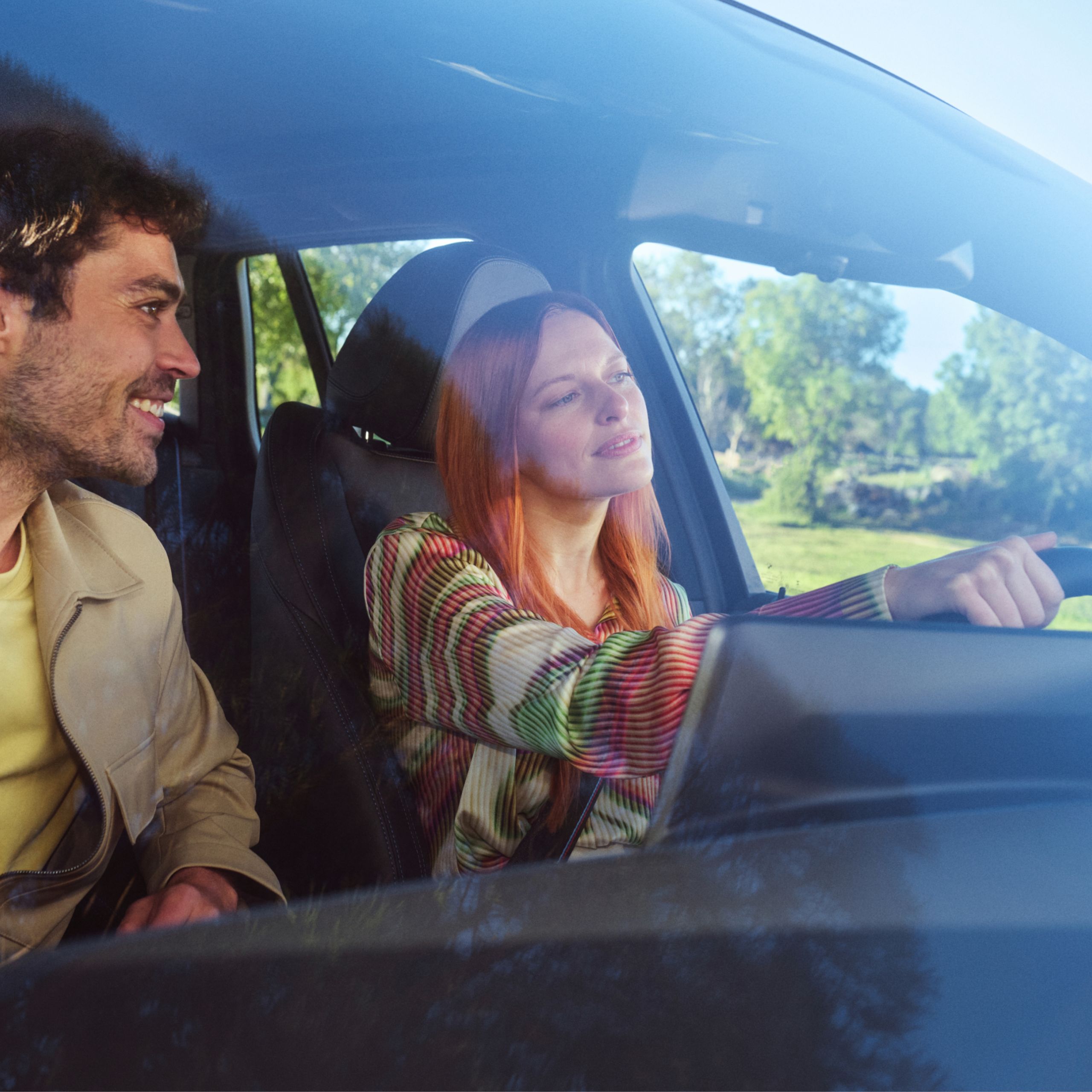 Two people are smiling happily while sitting in a BMW
