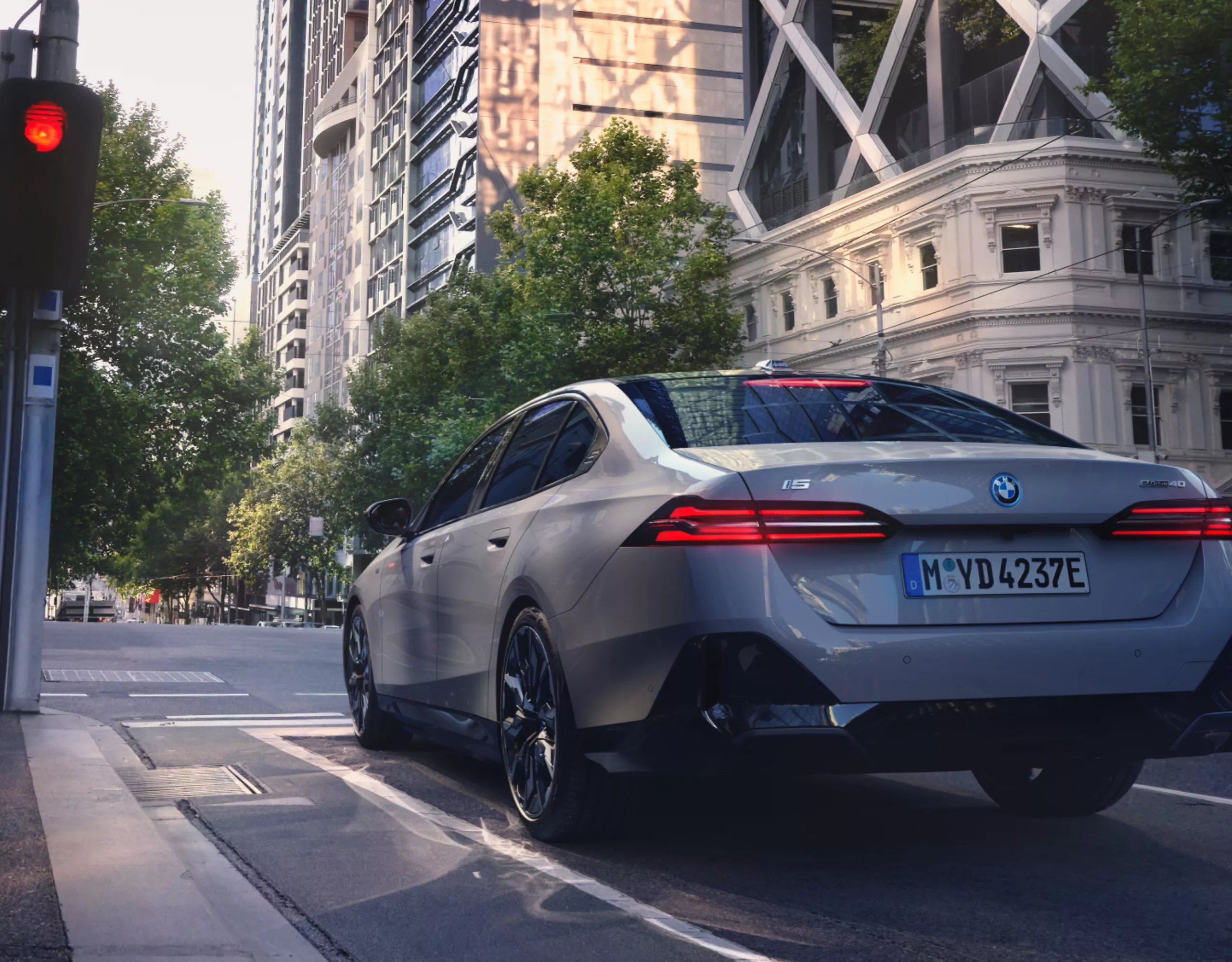 Een grijze BMW staat geparkeerd voor een rood licht in het stadscentrum