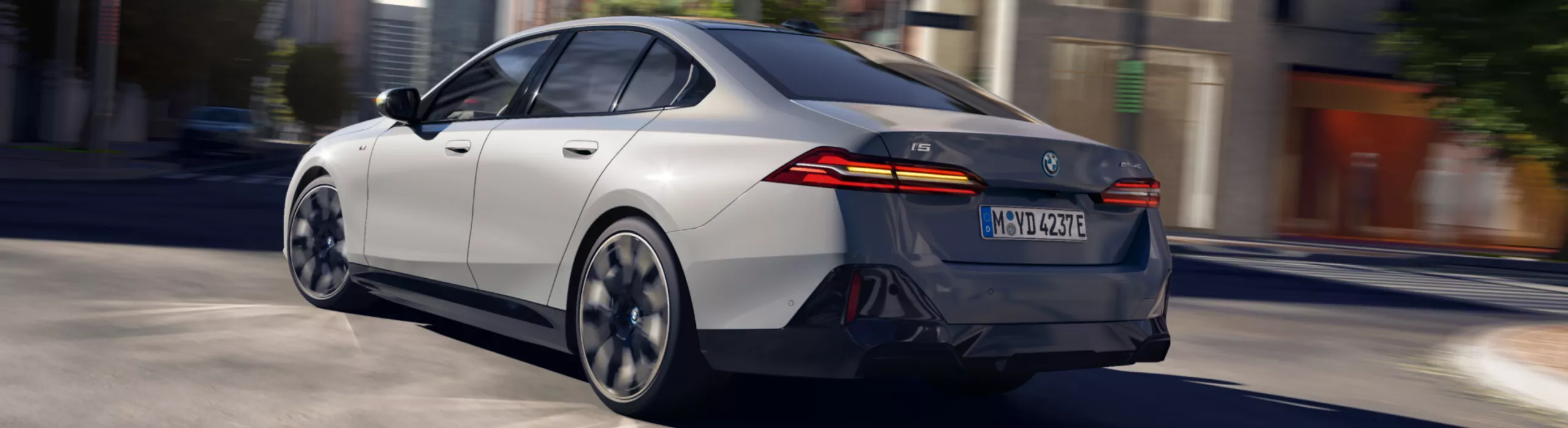 Het achteraanzicht van een grijze BMW i5 in de stad