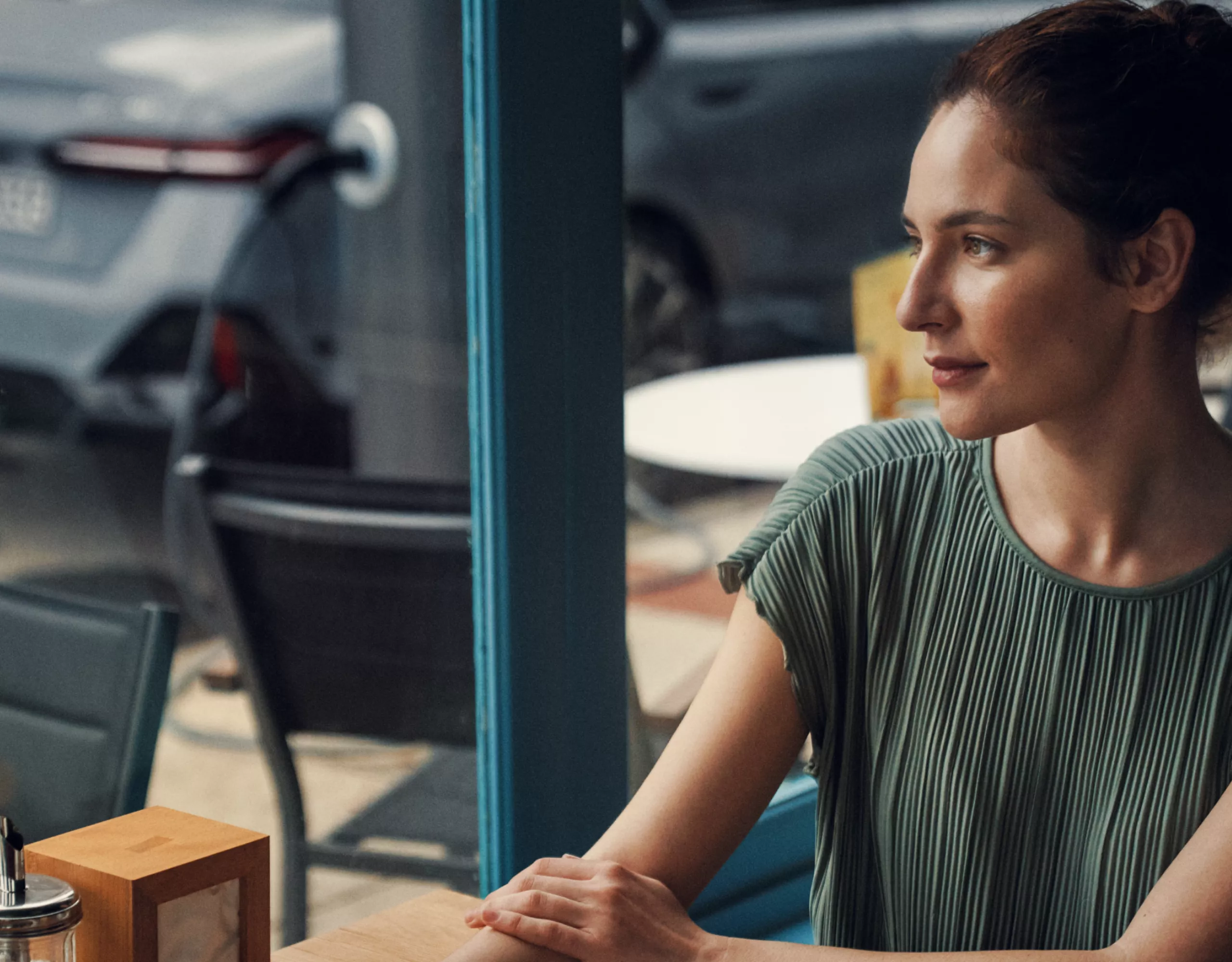 BMW i5 ツーリングが充電されている間、カフェでくつろいでいる女性