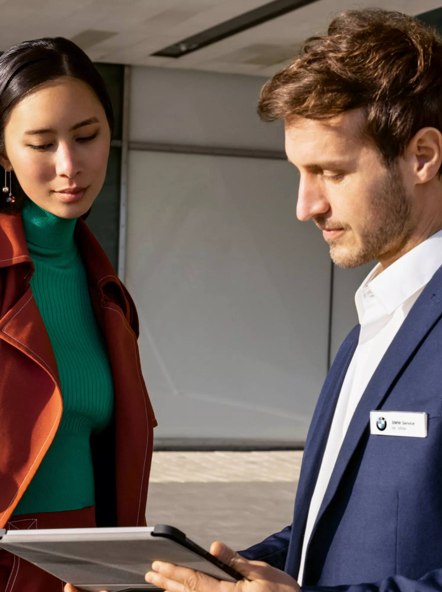 A woman and a man are looking at a tablet in a BMW dealership