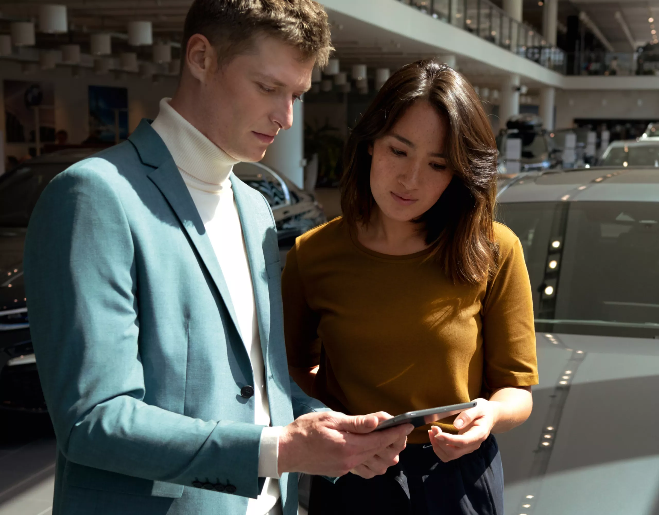 Zwei Personen schauen konzentriert auf ein Tablet in einem BMW Autohaus