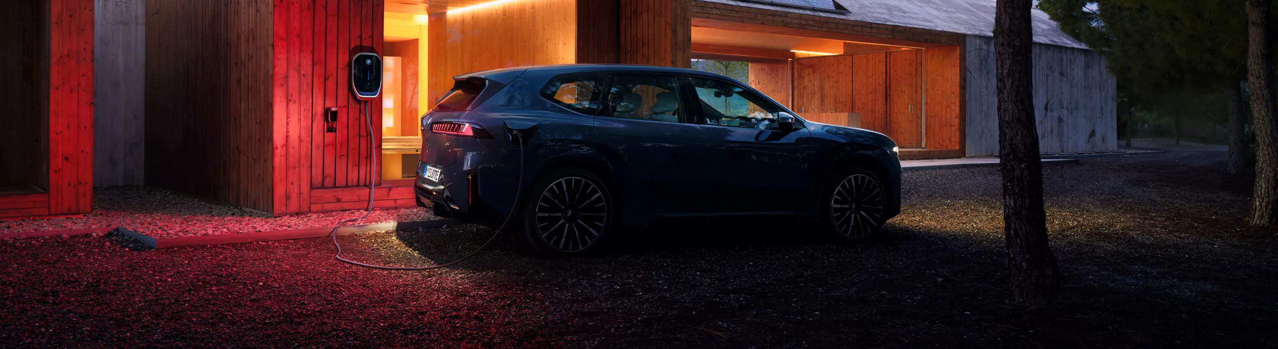 Ein BMW iX3 ist nachts an einer Wallbox angeschlossen