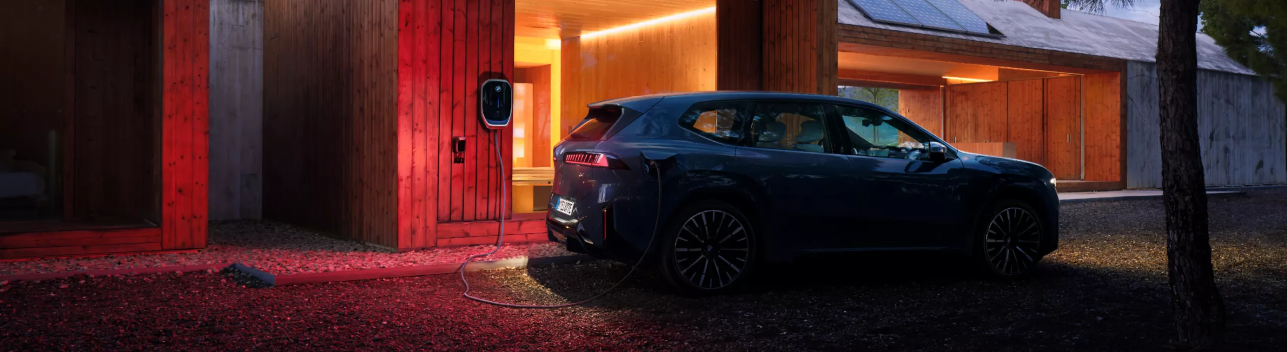 Ein BMW iX3 ist nachts an einer Wallbox angeschlossen