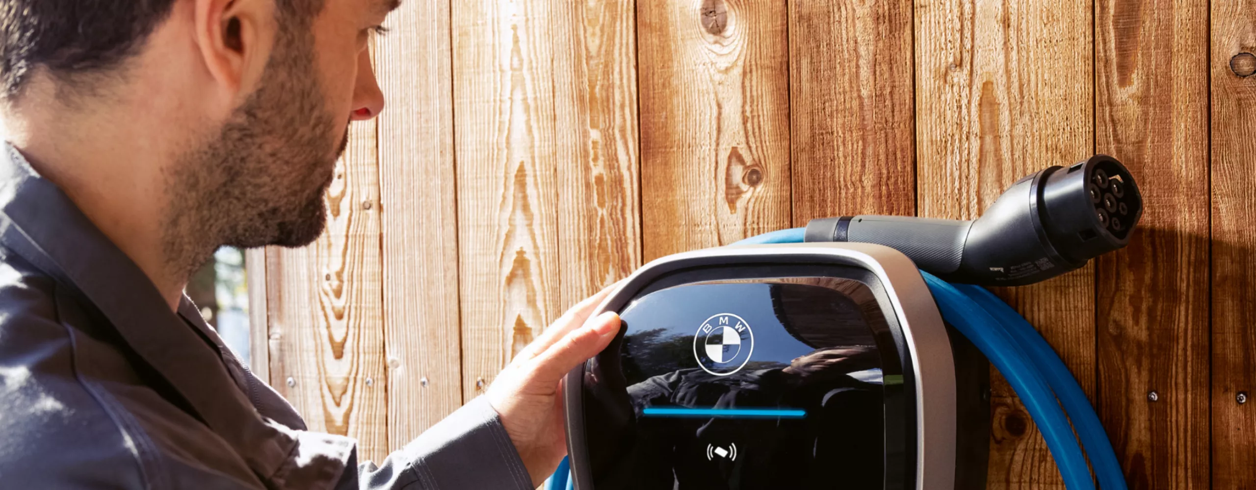 A person is connecting a charging cable to a BMW wallbox