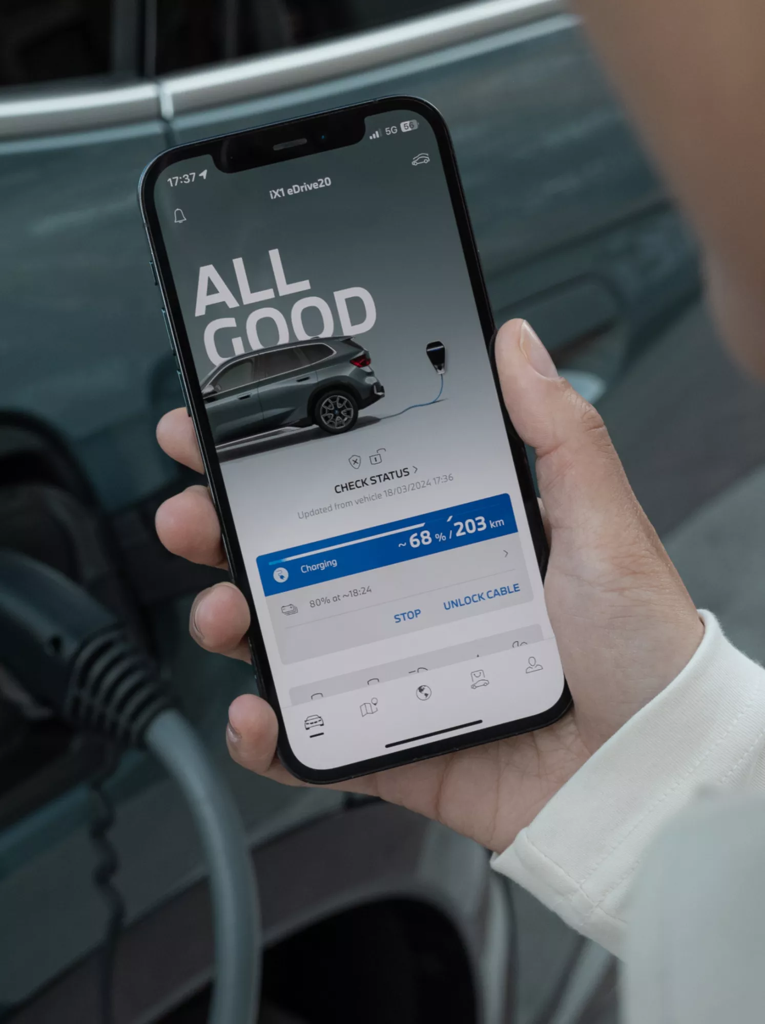 One hand is holding a smartphone with My BMW App open