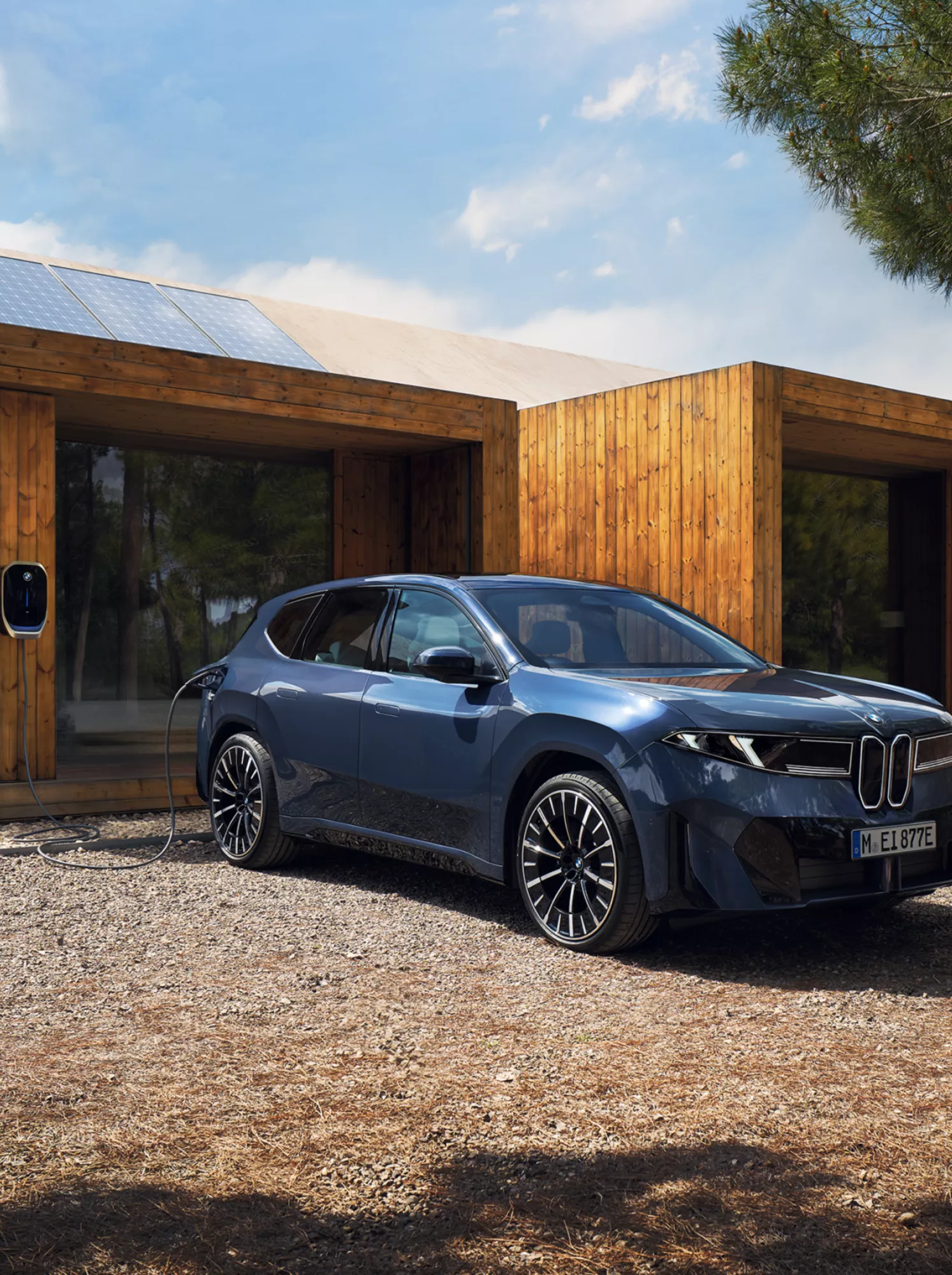 En kvinde går mod en BMW iX3, som er tilkoblet en wallbox