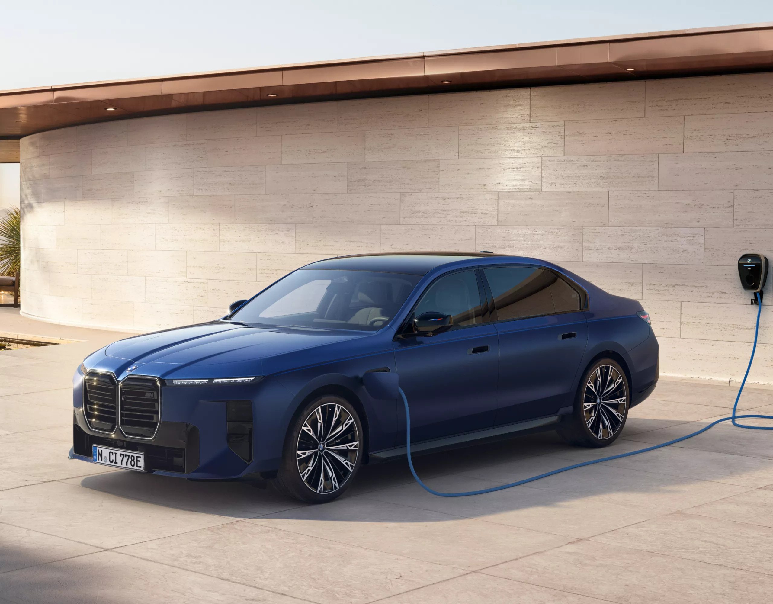 Une BMW est chargée sur une borne de recharge à domicile avec des plantes en arrière-plan 
